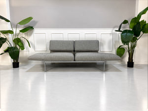 Gebrauchtes graues Brühl Roro Medium Designer Stoff Sofa vor einer Wand, stilvoll und modern eingerichtet.