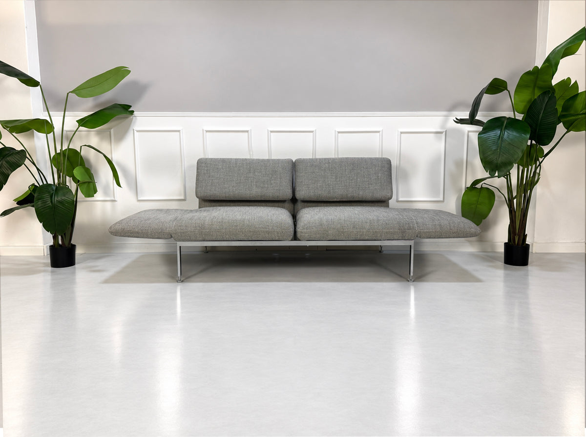 Gebrauchtes graues Brühl Roro Medium Designer Stoff Sofa vor einer Wand, stilvoll und modern eingerichtet.