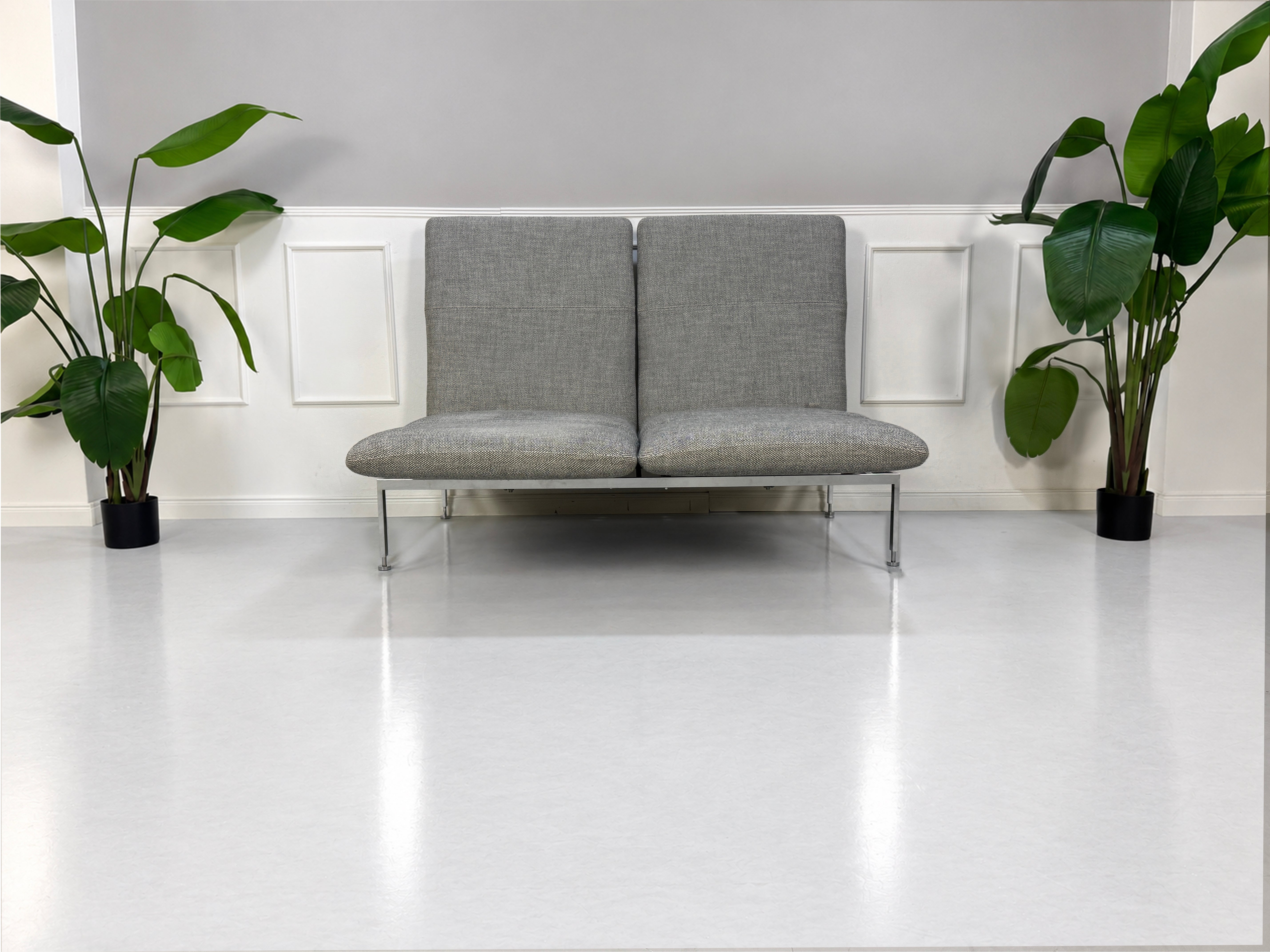 Gebrauchtes graues Brühl Roro Medium Designer Stoff Sofa vor einer Wand, stilvoll und modern eingerichtet.