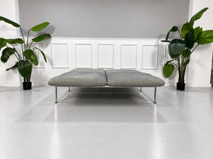Gebrauchtes graues Brühl Roro Medium Designer Stoff Sofa vor einer Wand, stilvoll und modern eingerichtet.