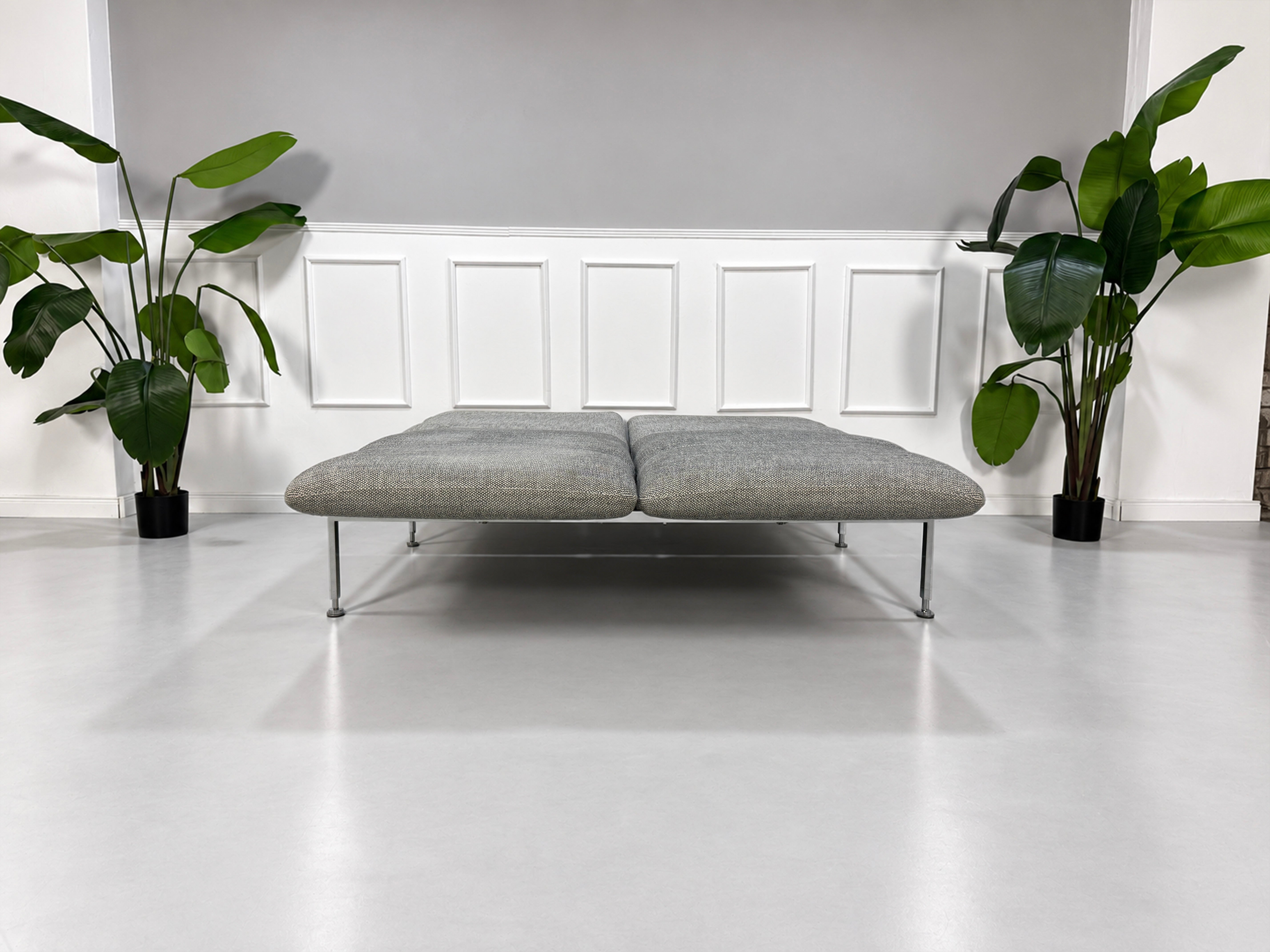 Gebrauchtes graues Brühl Roro Medium Designer Stoff Sofa vor einer Wand, stilvoll und modern eingerichtet.