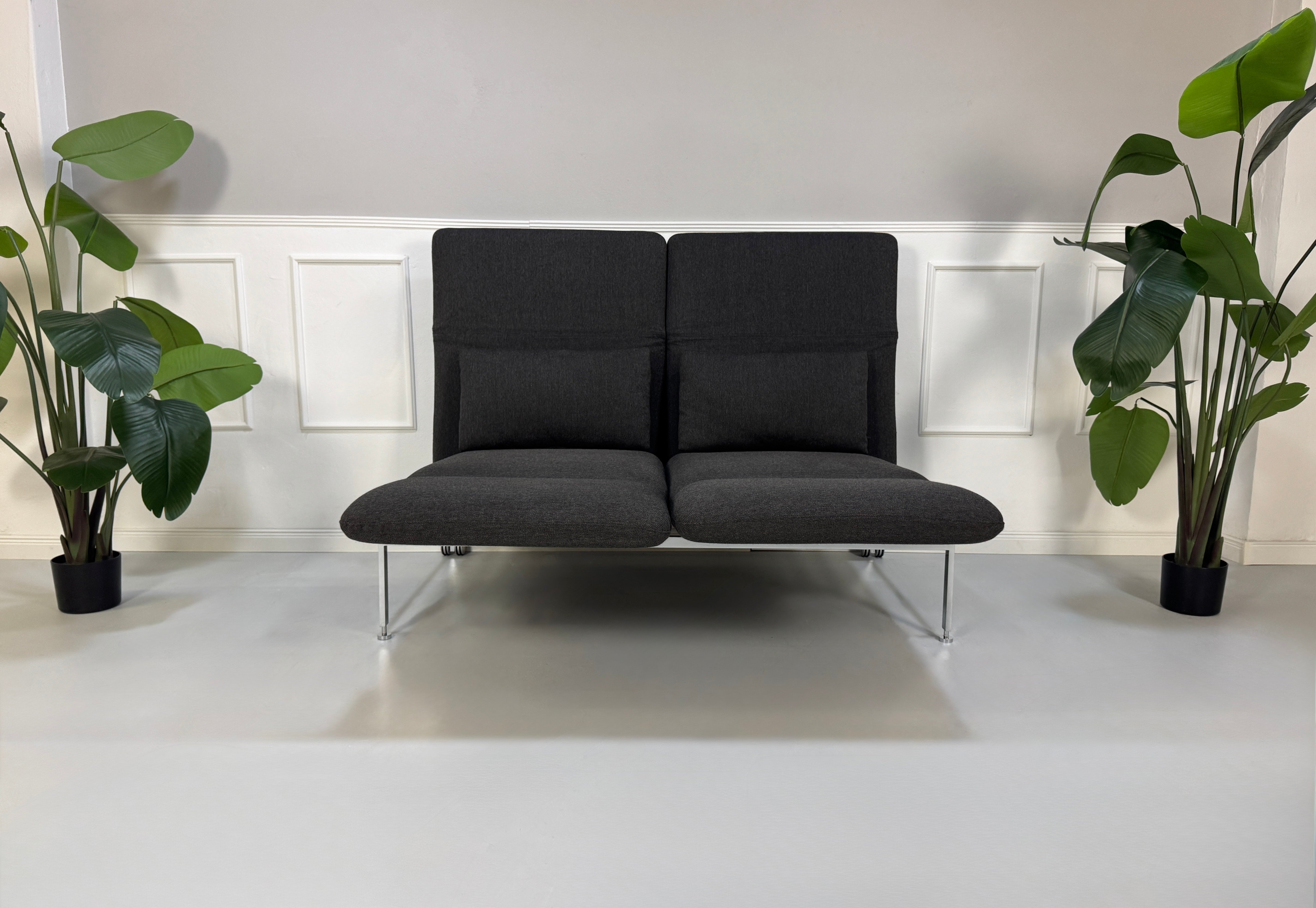 Gebrauchtes graues Brühl Roro Designer Stoff Sofa vor einer Wand, stilvoll und modern eingerichtet.