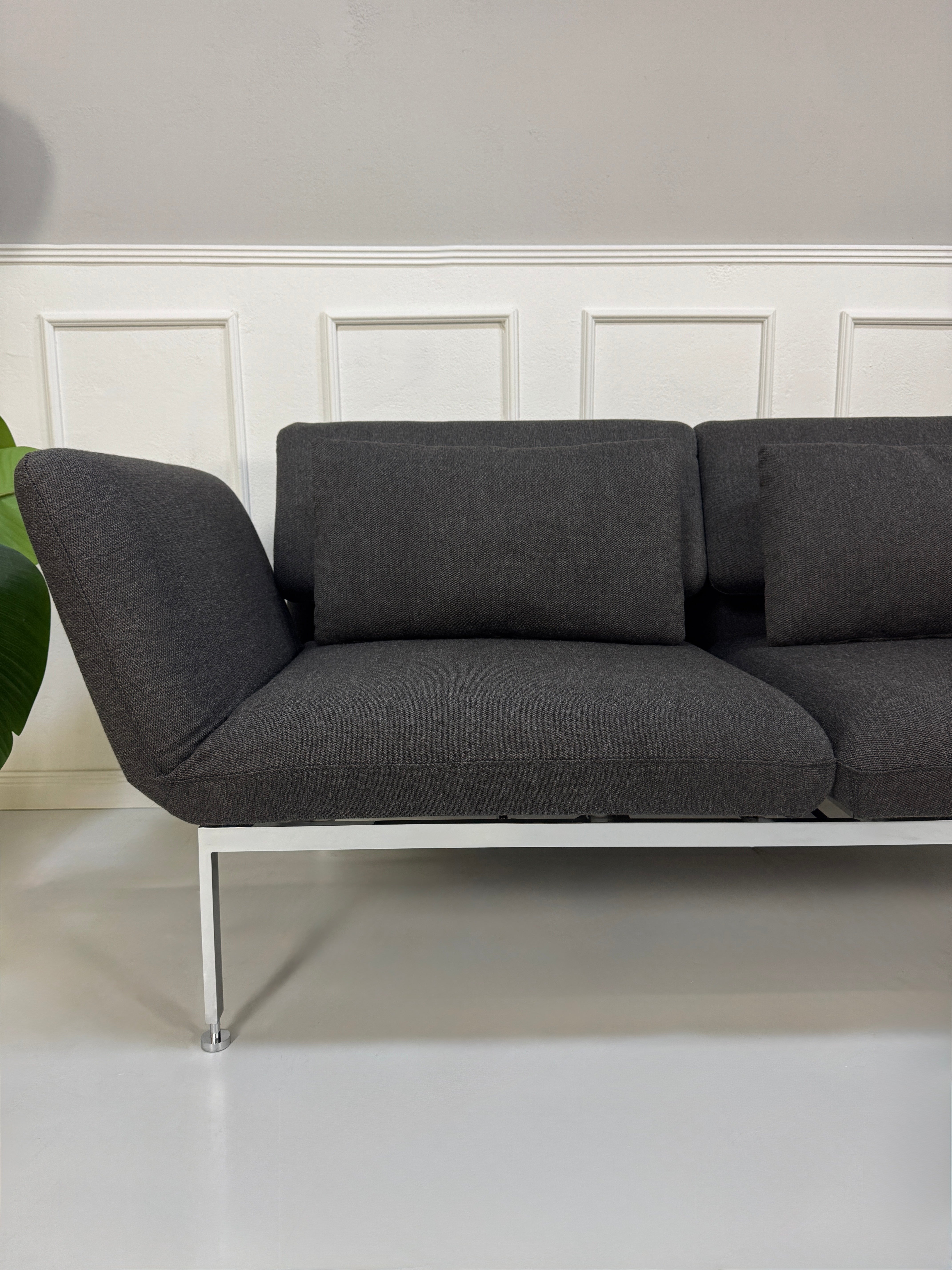 Gebrauchtes graues Brühl Roro Designer Stoff Sofa vor einer Wand, stilvoll und modern eingerichtet.