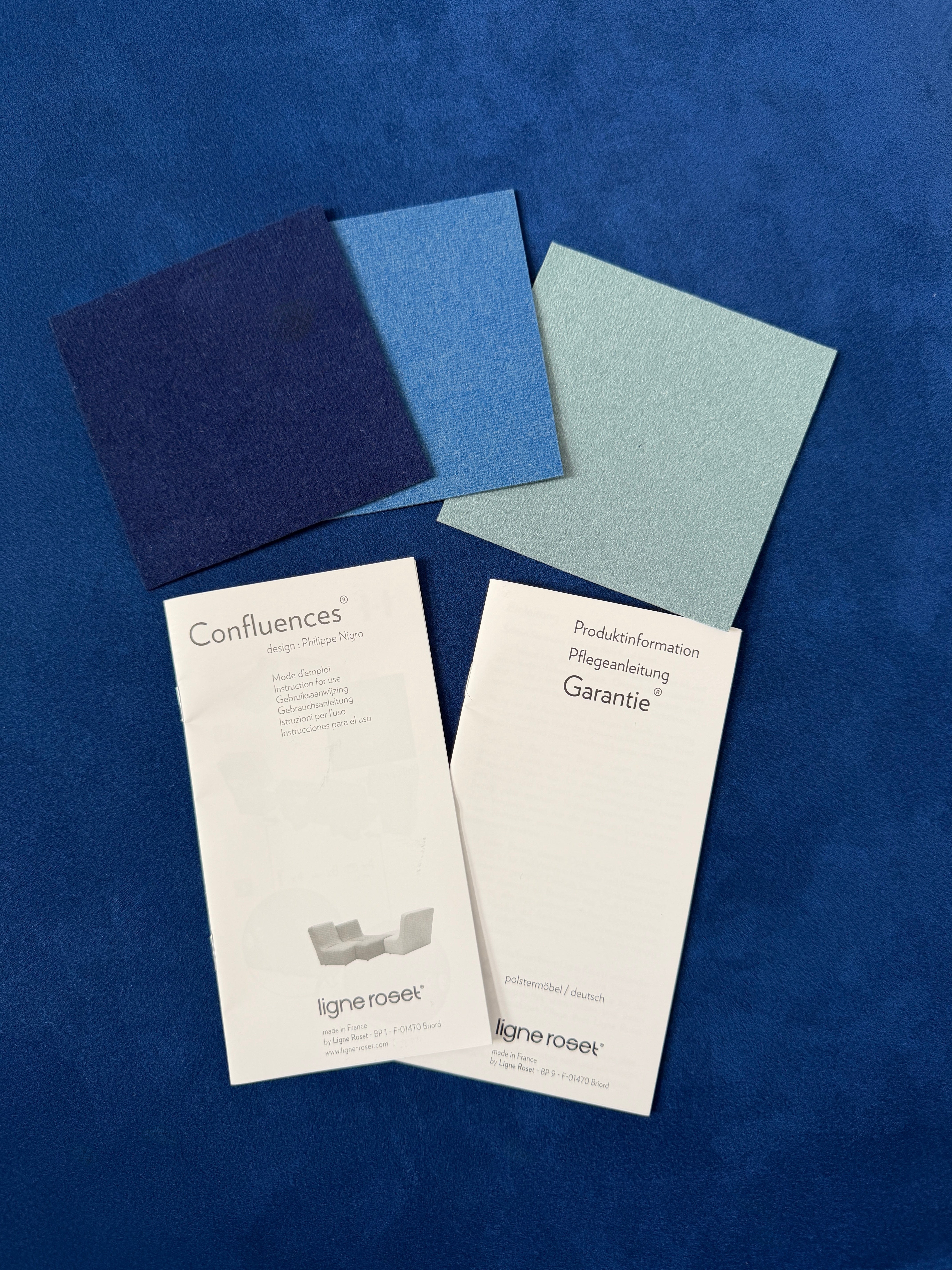 Gebrauchtes blaues Ligne Roset Confluences Designer Stoff Sofa vor einer Wand, stilvoll und modern eingerichtet.
