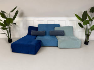 Gebrauchtes blaues Ligne Roset Confluences Designer Stoff Sofa vor einer Wand, stilvoll und modern eingerichtet.