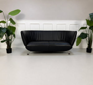 Gebrauchtes schwarzes De Sede DS 102 Designer Leder Sofa vor einer Wand, stilvoll und modern eingerichtet.