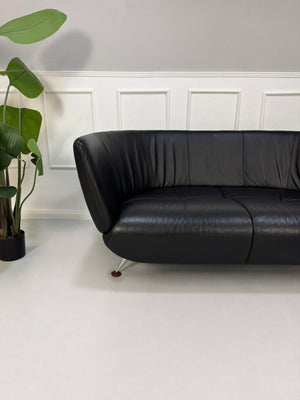 Gebrauchtes schwarzes De Sede DS 102 Designer Leder Sofa vor einer Wand, stilvoll und modern eingerichtet.