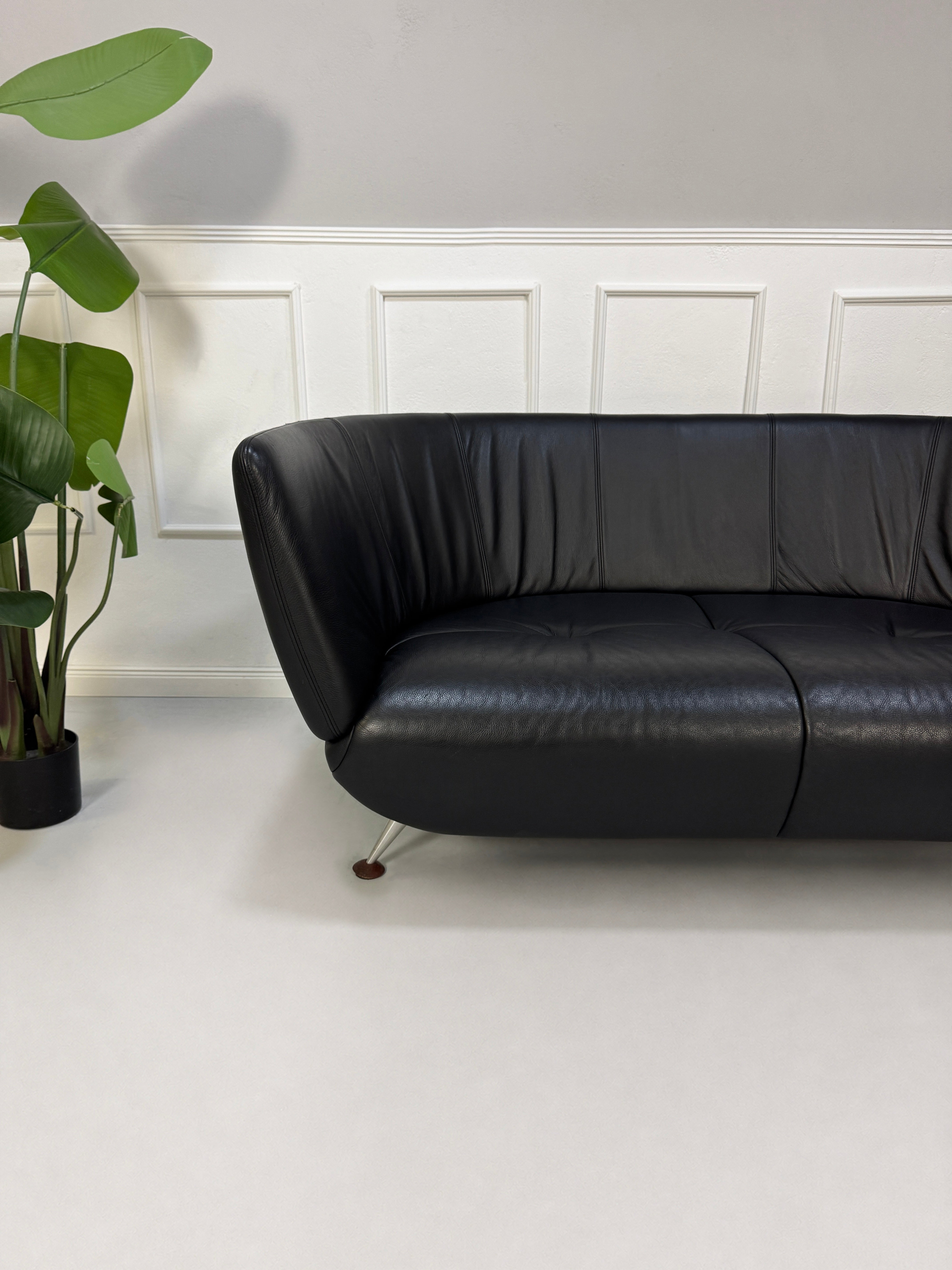 Gebrauchtes schwarzes De Sede DS 102 Designer Leder Sofa vor einer Wand, stilvoll und modern eingerichtet.