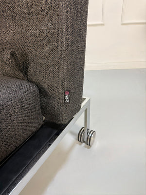 Gebrauchtes graues Brühl Roro Soft Designer Stoff Sofa vor einer Wand, stilvoll und modern eingerichtet.