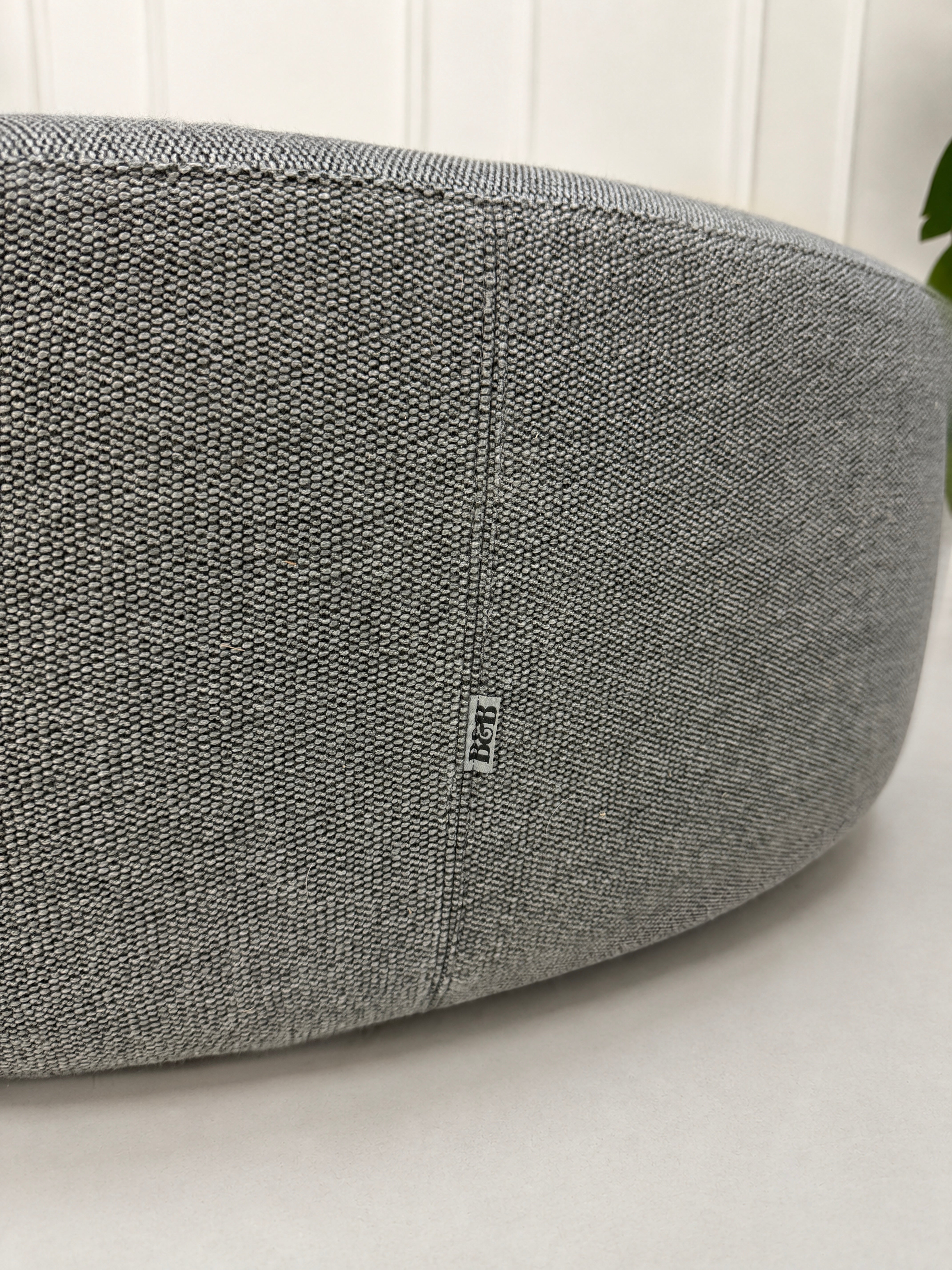 Gebrauchter grauer B&B Italia Charles Designer Stoff Hocker vor einer Wand, stilvoll und modern eingerichtet.