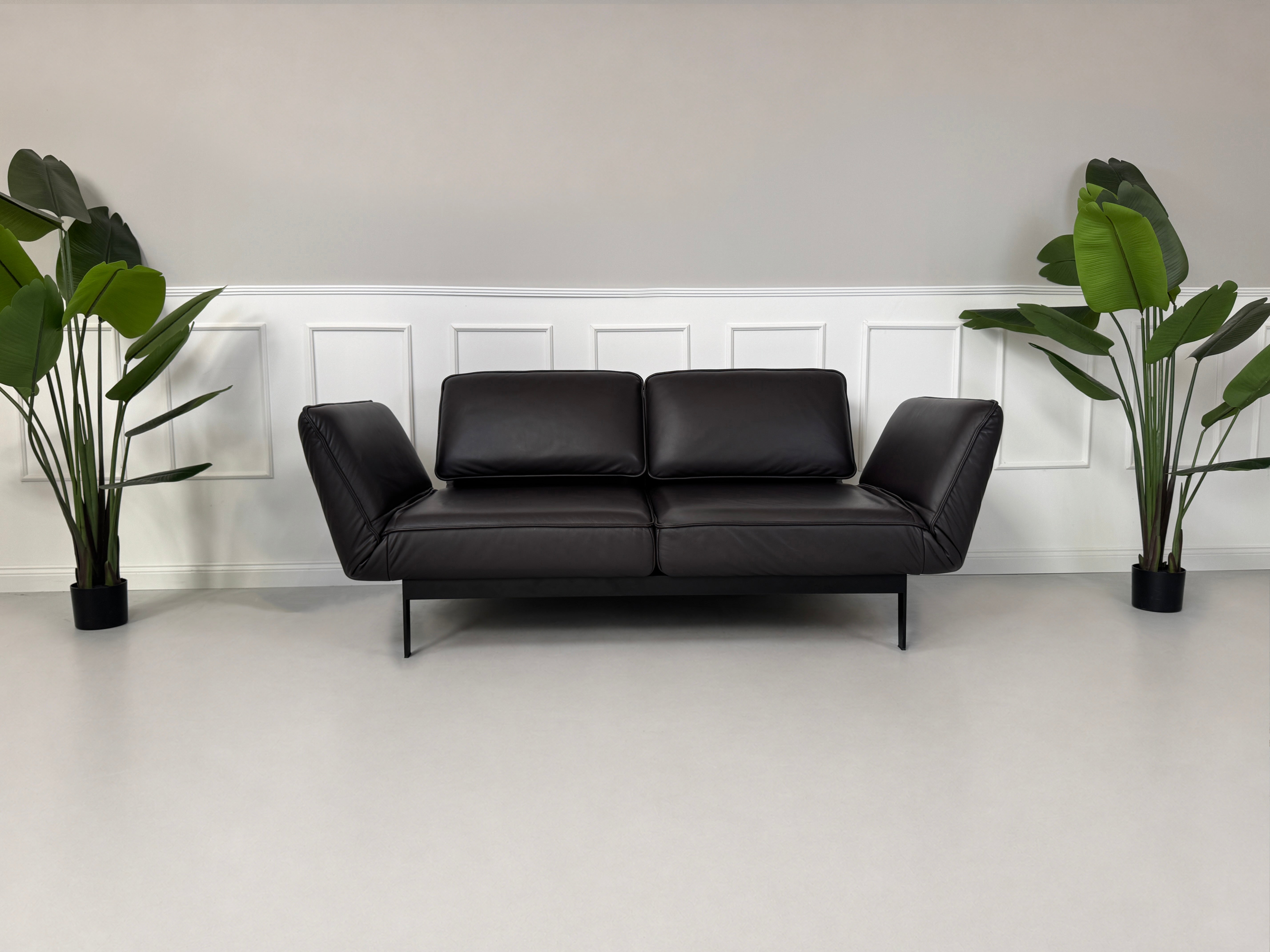 Gebrauchtes Schwarz Braun Rolf Benz Mera Designer Leder Sofa vor einer Wand, stilvoll und modern eingerichtet.