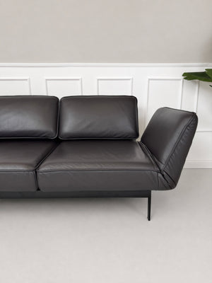 Gebrauchtes schwarz-braunes Rolf Benz Mera Designer Leder Sofa vor einer Wand, stilvoll und modern eingerichtet.