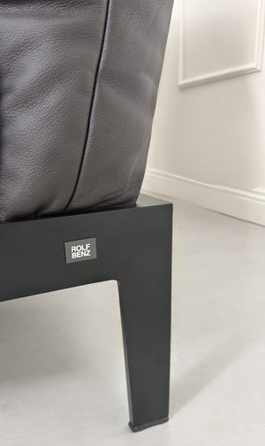 Gebrauchtes schwarz-braunes Rolf Benz Mera Designer Leder Sofa vor einer Wand, stilvoll und modern eingerichtet.