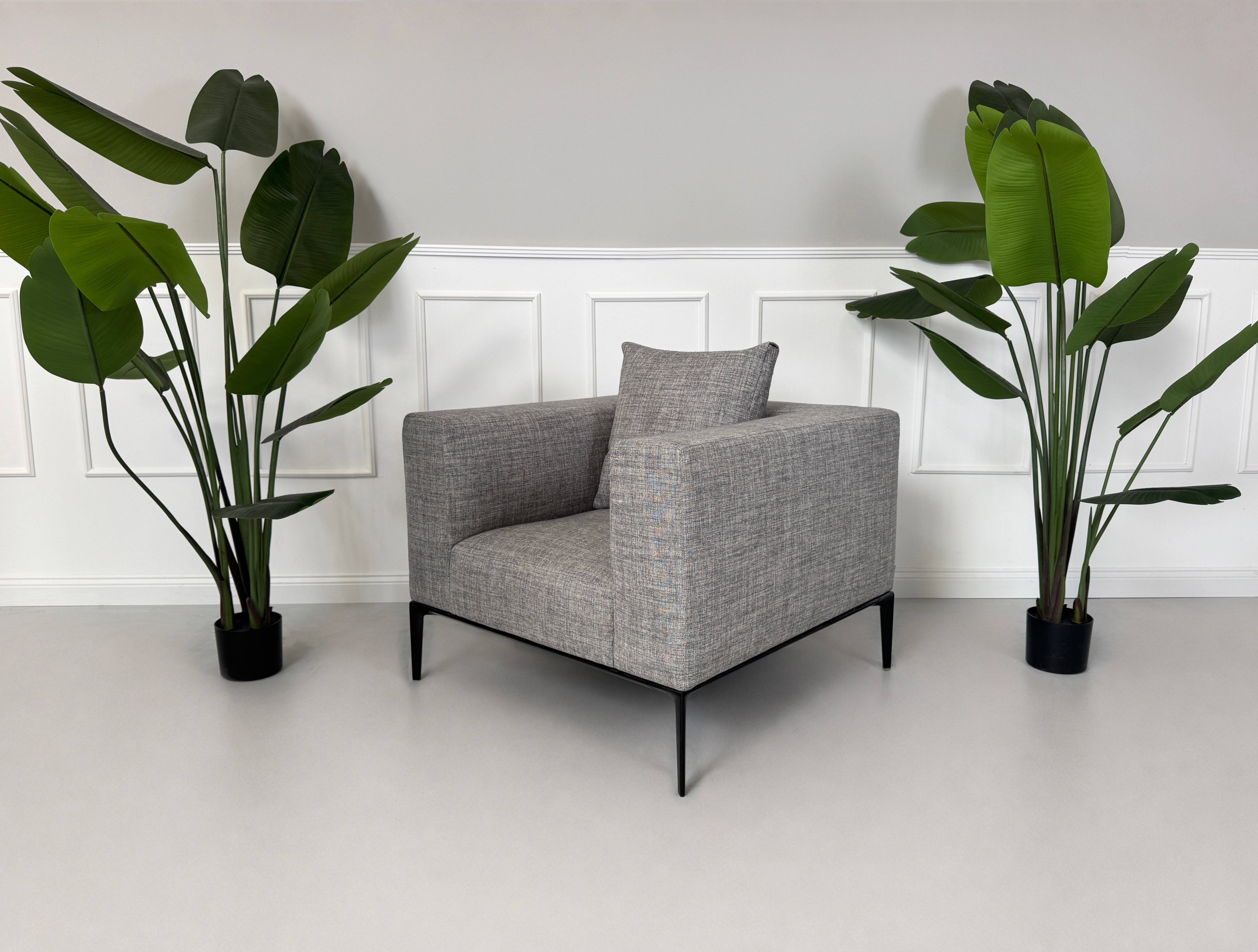 Gebrauchter grauer Walter Knoll Jaan Living Designer Stoff Sessel vor einer Wand, stilvoll und modern eingerichtet.