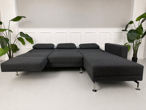 Gebrauchtes graues Brühl Moule Designer Stoff Sofa vor einer Wand, stilvoll und modern eingerichtet.