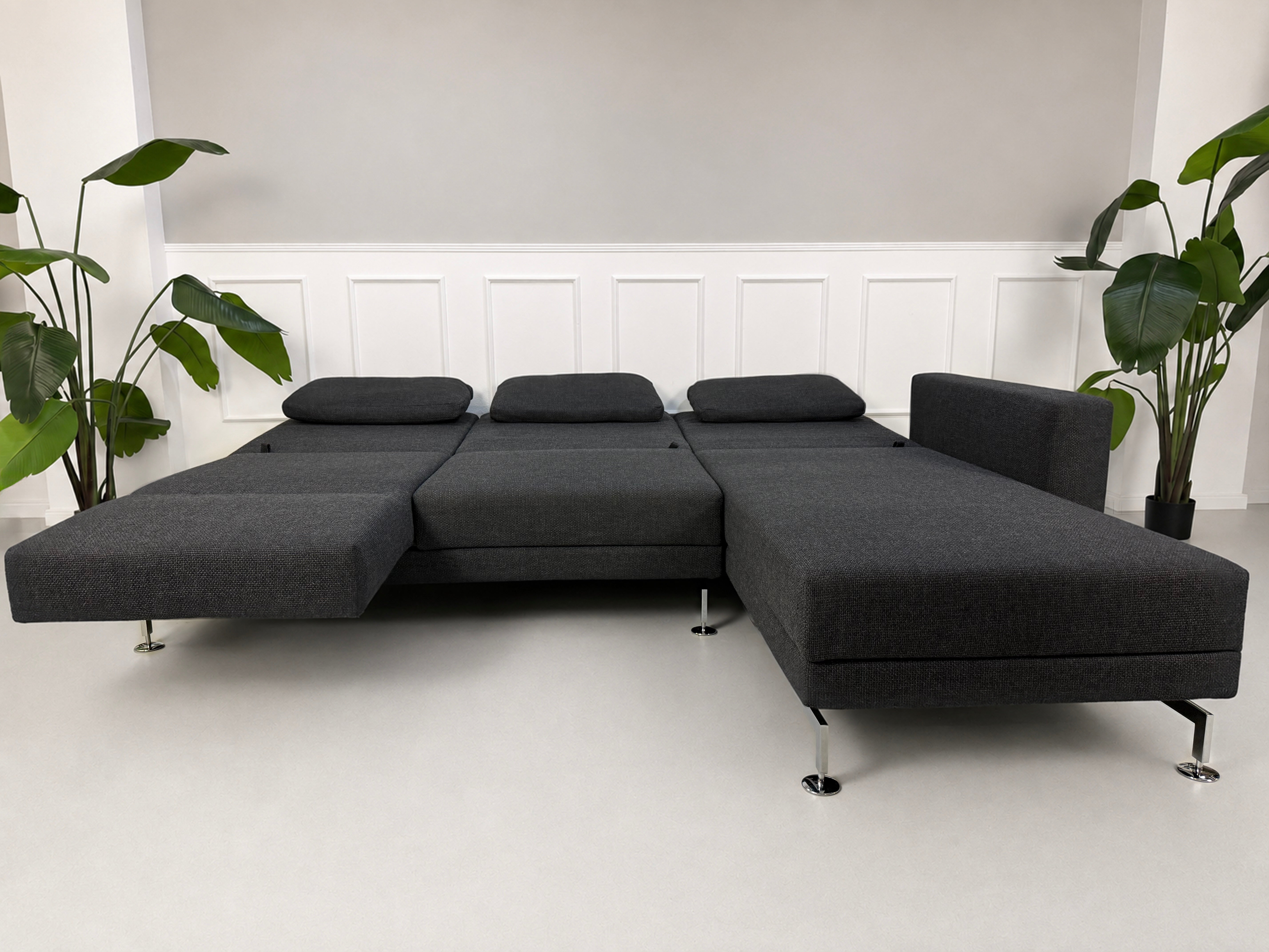 Gebrauchtes graues Brühl Moule Designer Stoff Sofa vor einer Wand, stilvoll und modern eingerichtet.