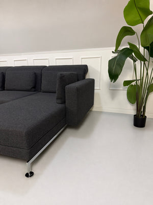 Gebrauchtes graues Brühl Moule Designer Stoff Sofa vor einer Wand, stilvoll und modern eingerichtet.