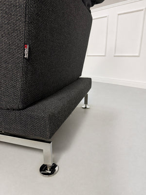 Gebrauchtes graues Brühl Moule Designer Stoff Sofa vor einer Wand, stilvoll und modern eingerichtet.