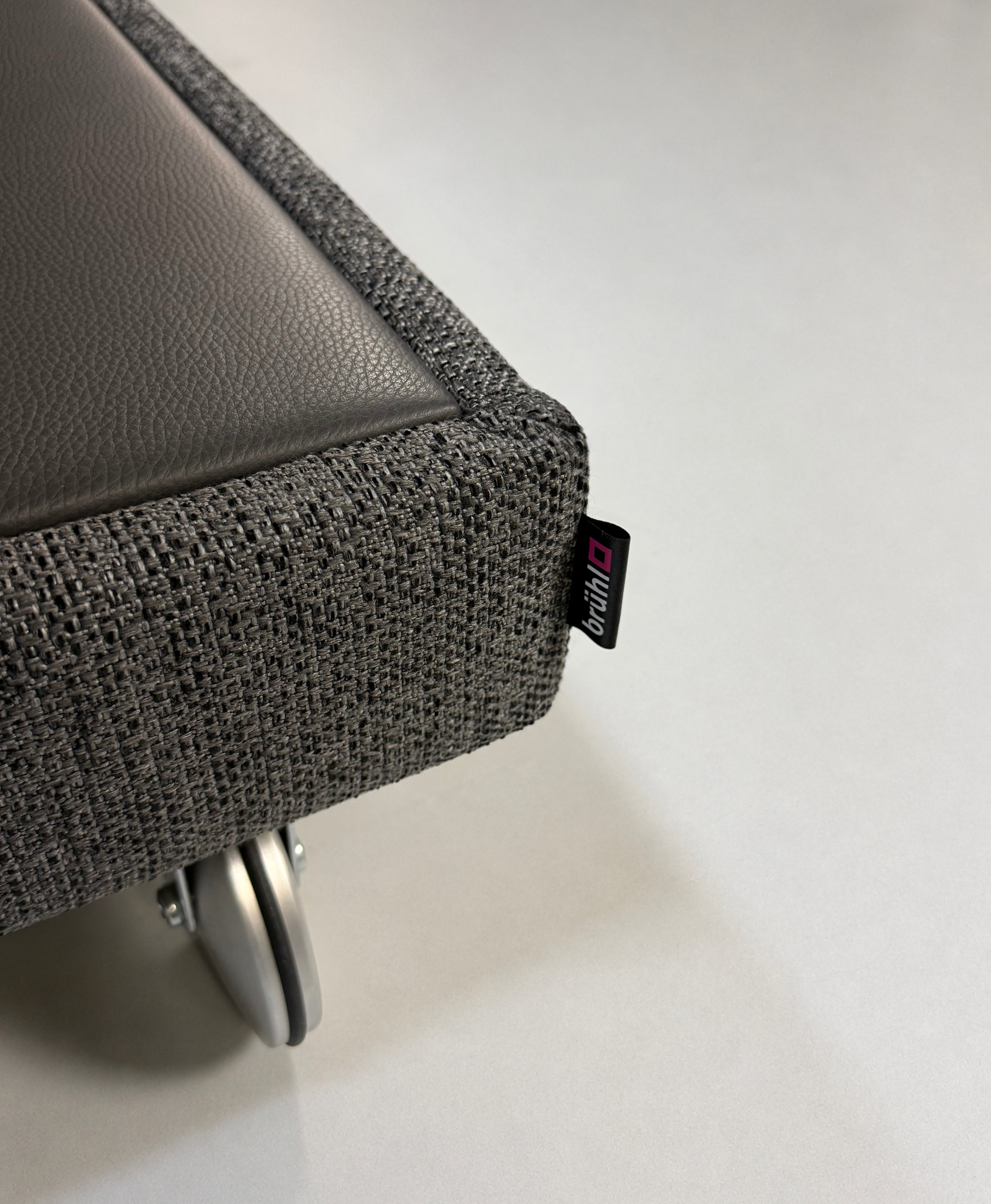 Gebrauchtes graues Brühl Fourtwo Designer Stoff Sofa vor einer Wand, stilvoll und modern eingerichtet.