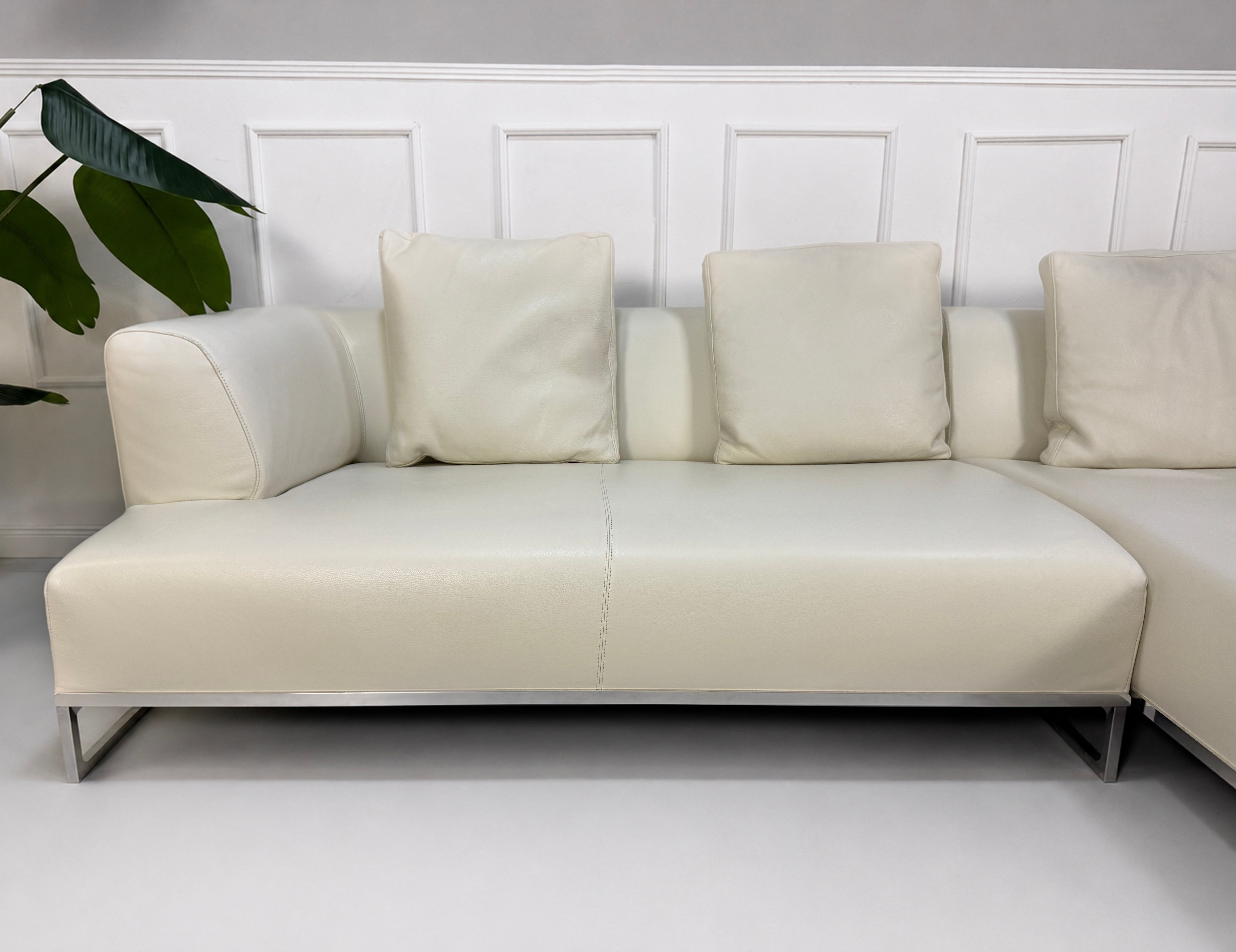 Gebrauchtes weißes B&B Italia Solo Designer Leder Sofa vor einer Wand, stilvoll und modern eingerichtet.