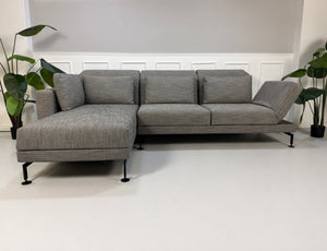 Gebrauchtes graues Brühl Moule Designer Stoff Sofa vor einer Wand, stilvoll und modern eingerichtet.
