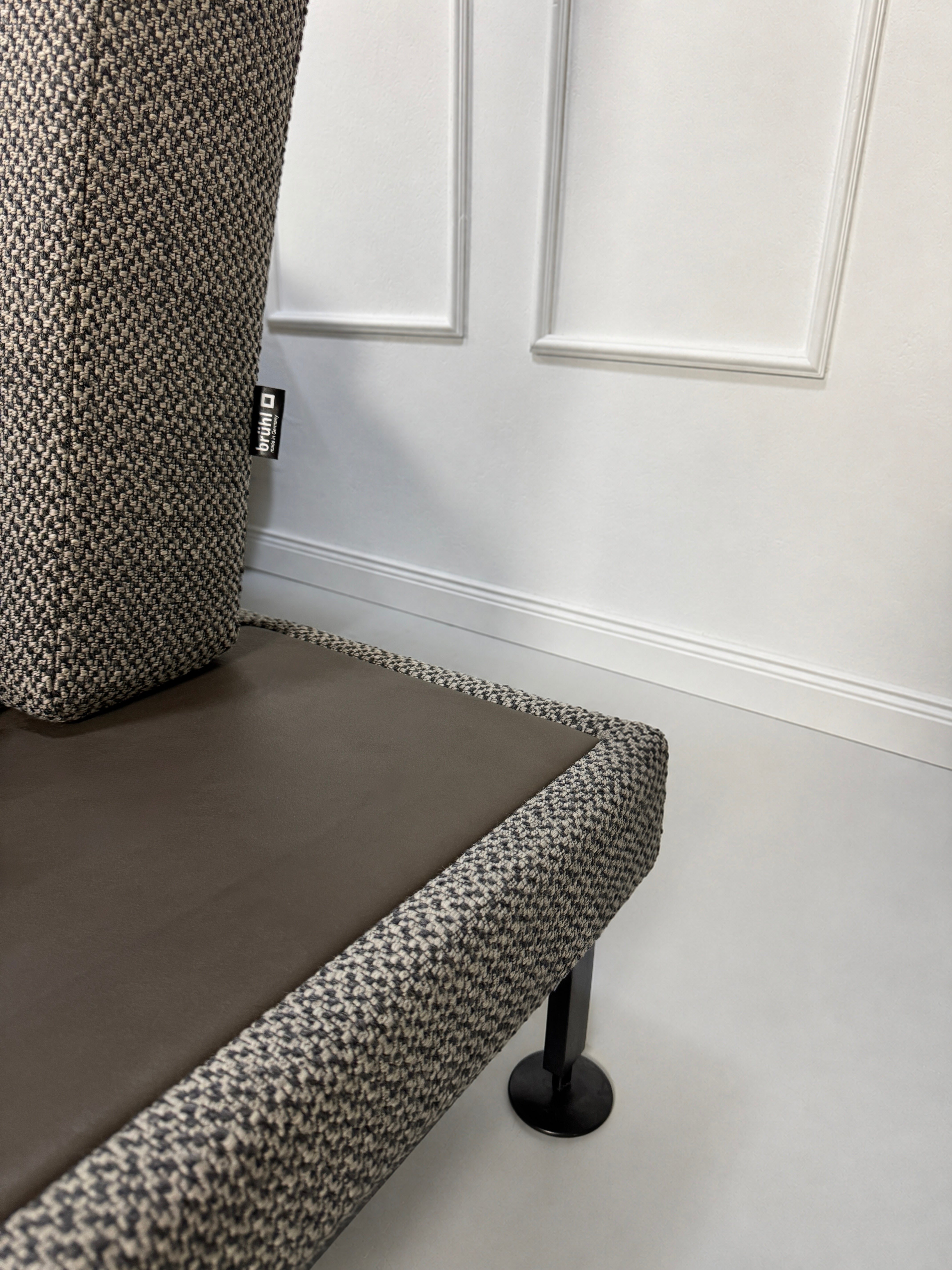 Gebrauchtes graues Brühl Moule Designer Stoff Sofa vor einer Wand, stilvoll und modern eingerichtet.