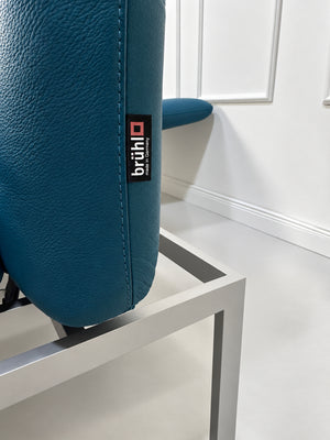 Gebrauchtes blaues Brühl Roro Medium Designer Leder Sofa vor einer Wand, stilvoll und modern eingerichtet.