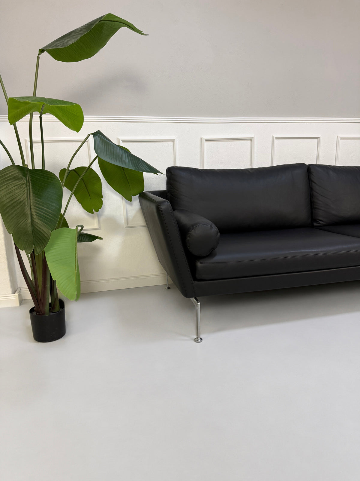 Gebrauchtes schwarzes Vitra Suita Designer Leder Sofa, Detailansicht von Armlehne und Nackenrolle.