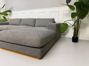 Gebrauchtes graues Bolia Sepia Designer Stoff Sofa vor einer Wand, stilvoll und modern eingerichtet.
