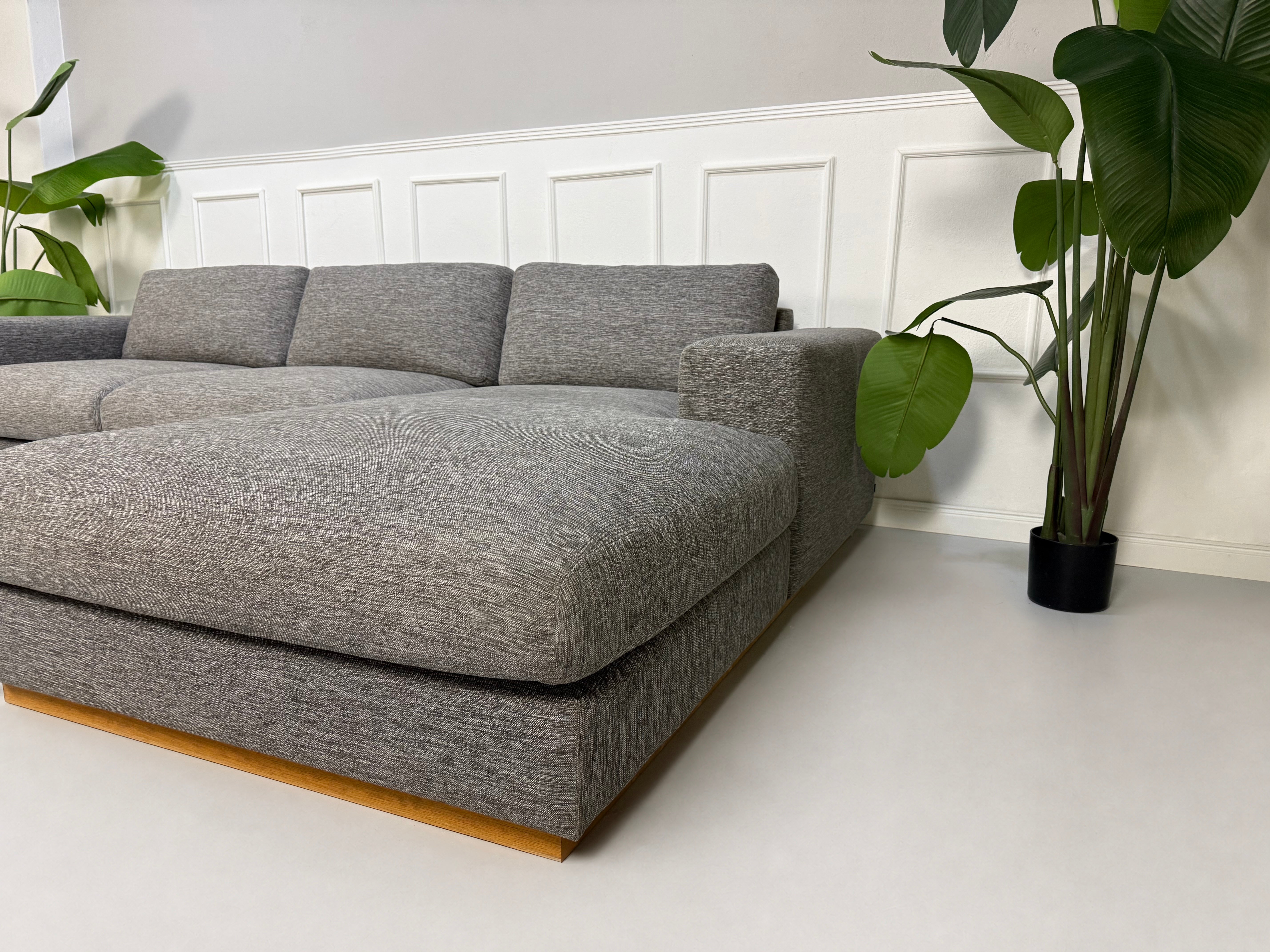 Gebrauchtes graues Bolia Sepia Designer Stoff Sofa vor einer Wand, stilvoll und modern eingerichtet.