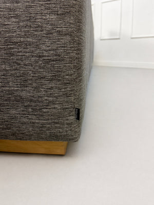 Gebrauchtes graues Bolia Sepia Designer Stoff Sofa vor einer Wand, stilvoll und modern eingerichtet.