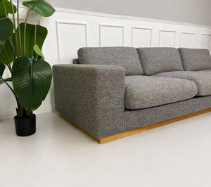 Gebrauchtes graues Bolia Sepia Designer Stoff Sofa vor einer Wand, stilvoll und modern eingerichtet.