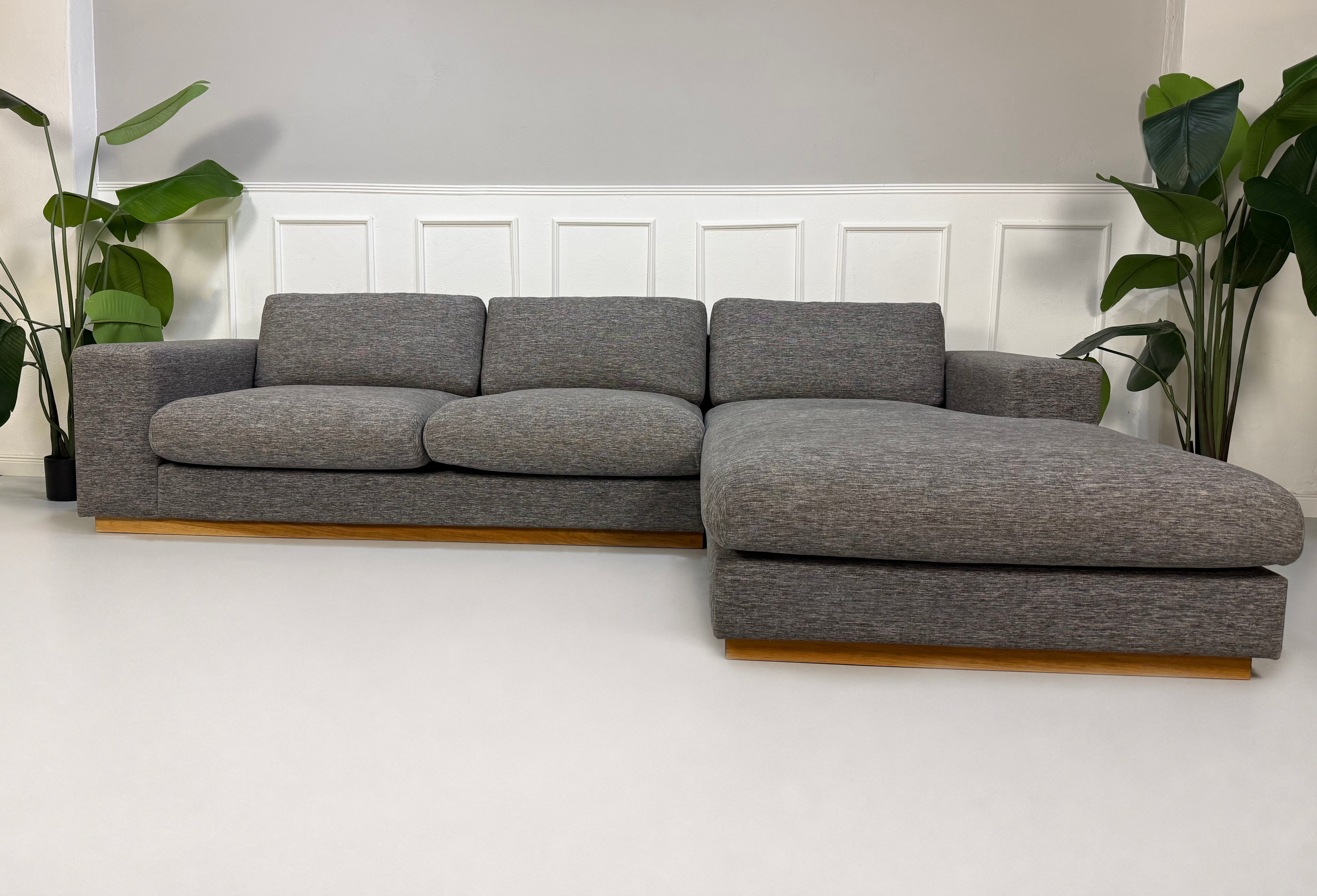 Gebrauchtes graues Bolia Sepia Designer Stoff Sofa vor einer Wand, stilvoll und modern eingerichtet.