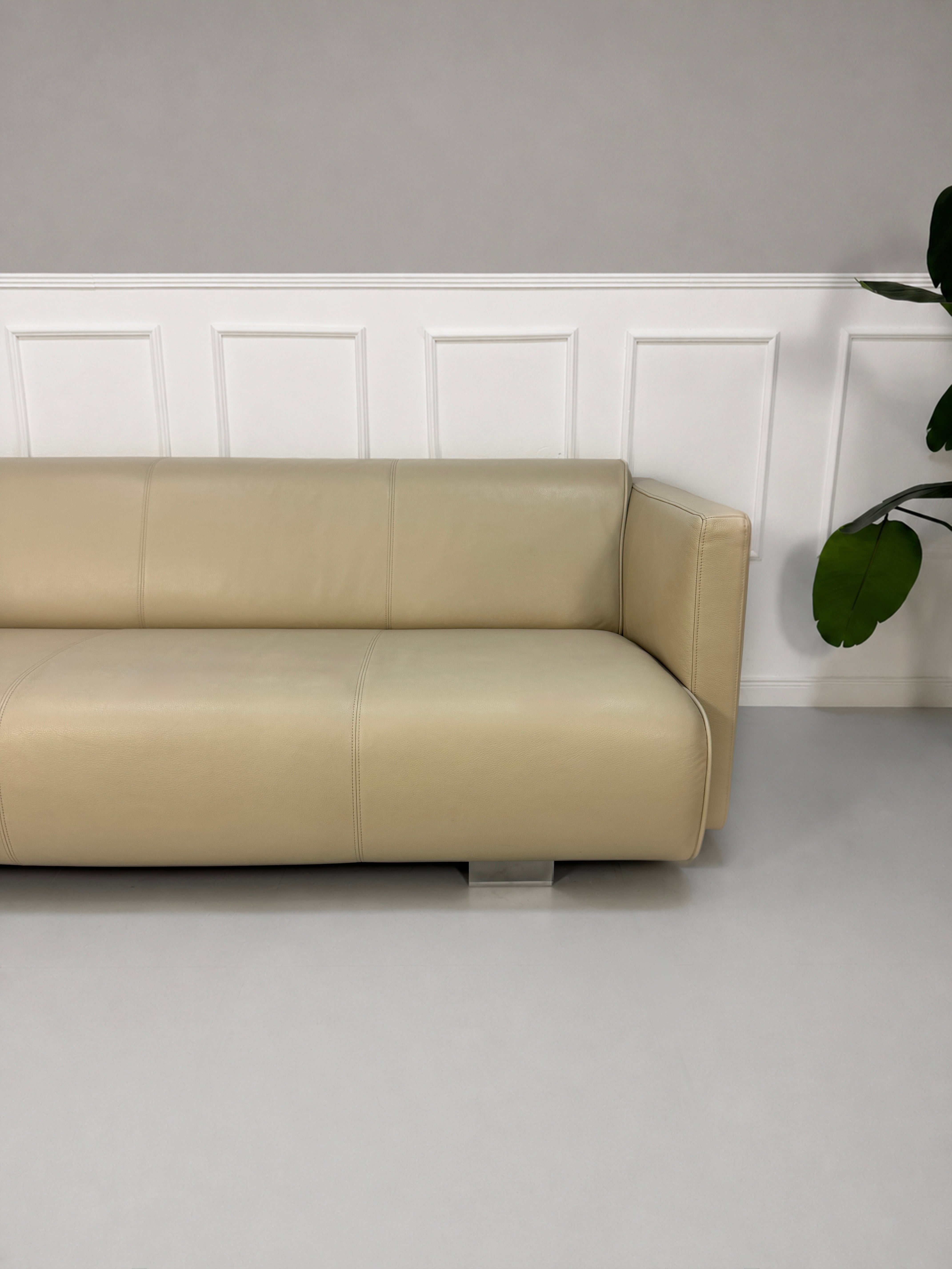 Gebrauchtes beiges Rolf Benz 6300 Designer Leder Sofa vor einer Wand, stilvoll und modern eingerichtet.