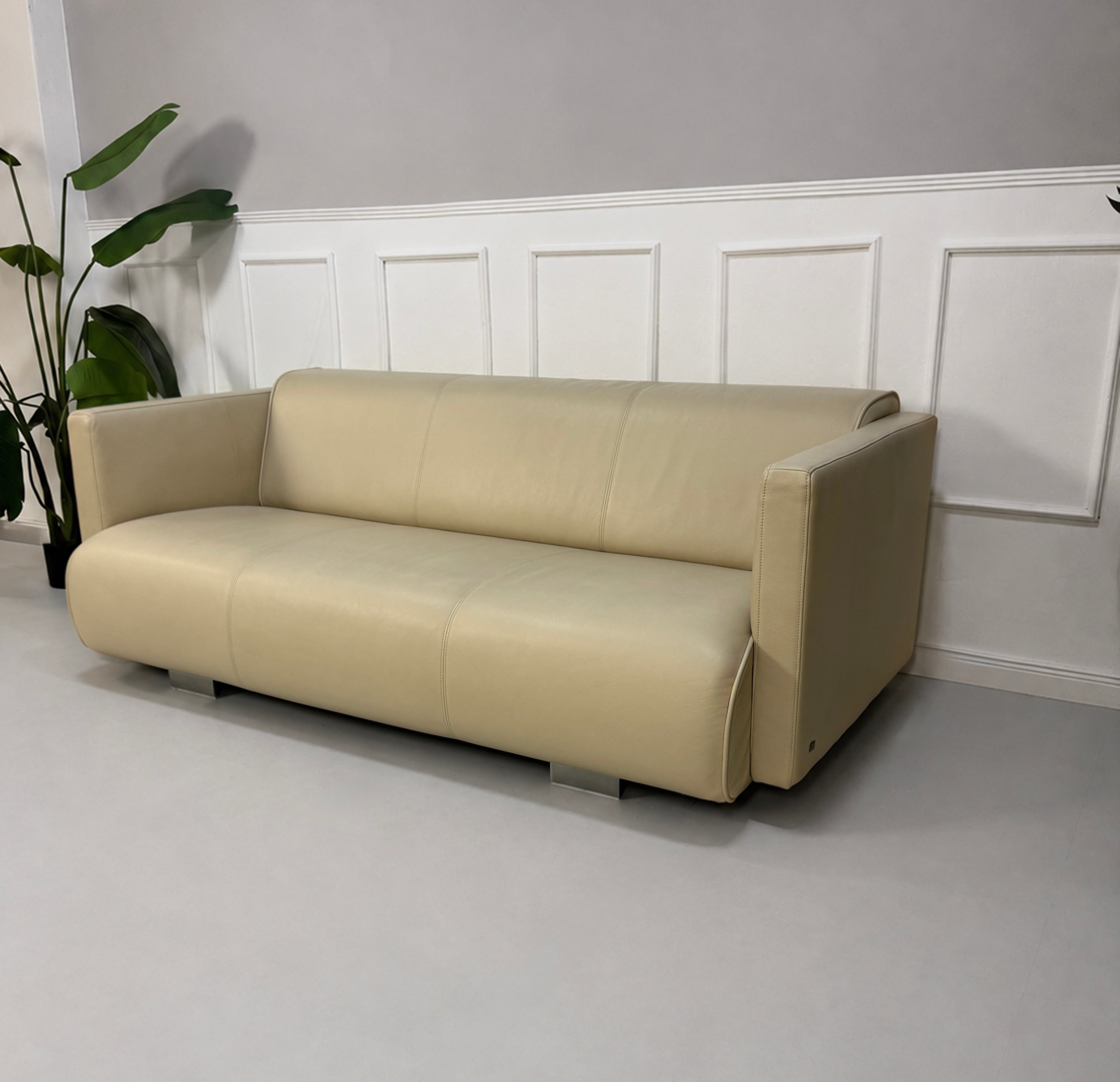 Gebrauchtes beiges Rolf Benz 6300 Designer Leder Sofa vor einer Wand, stilvoll und modern eingerichtet.