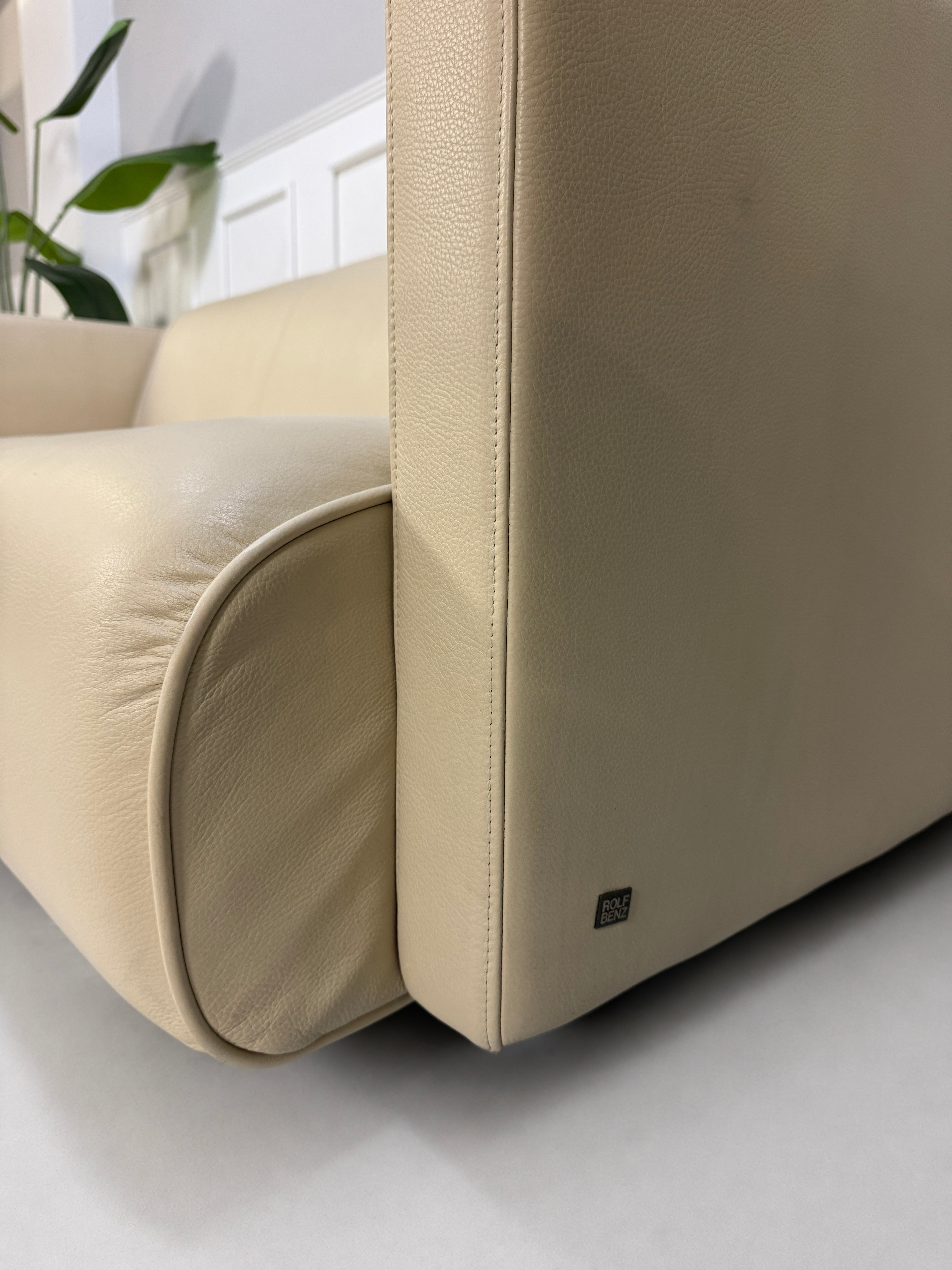 Gebrauchtes beiges Rolf Benz 6300 Designer Leder Sofa vor einer Wand, stilvoll und modern eingerichtet.