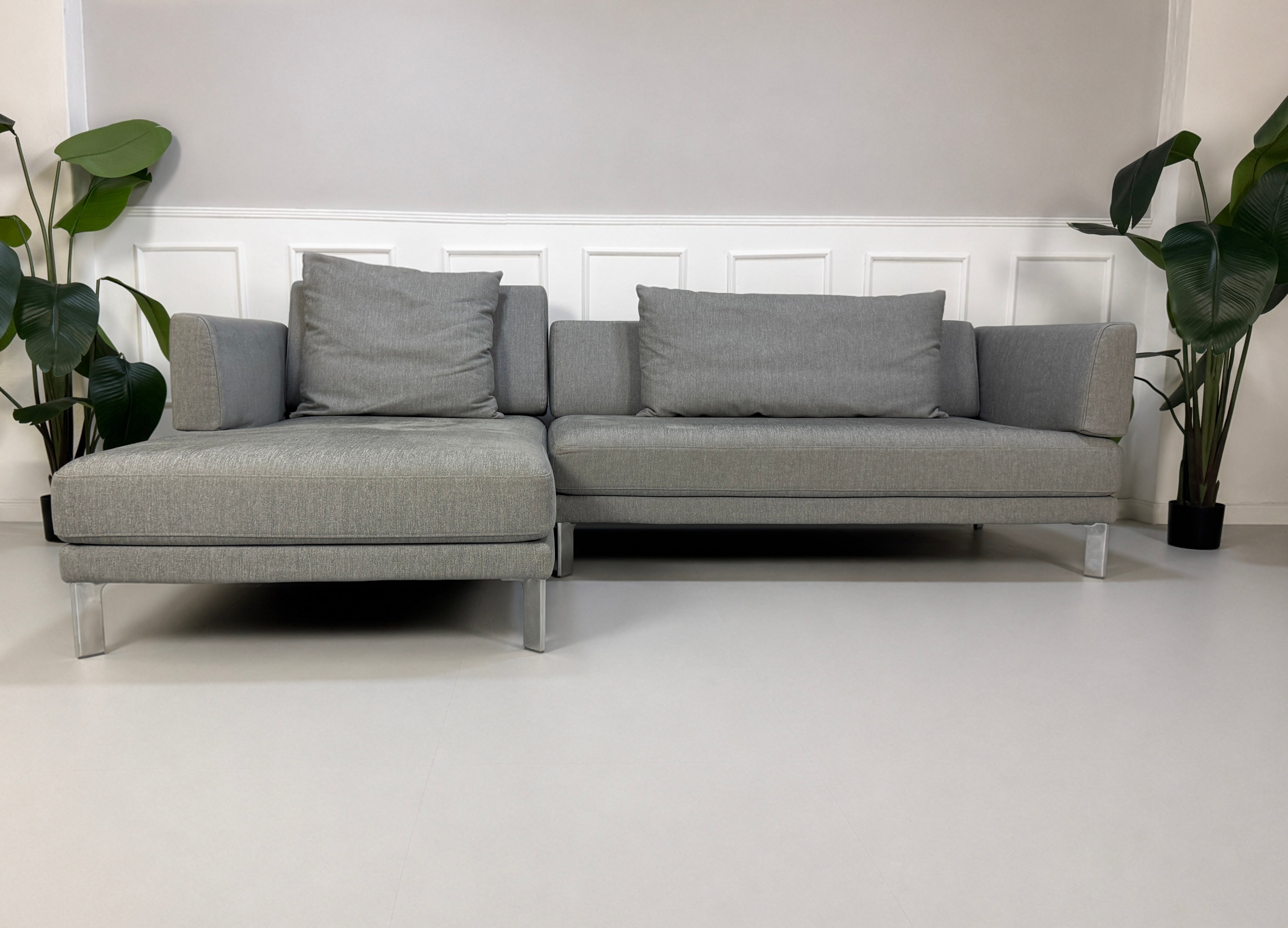 Gebrauchtes graues Rolf Benz Sento Designer Stoff Sofa vor einer Wand, stilvoll und modern eingerichtet.
