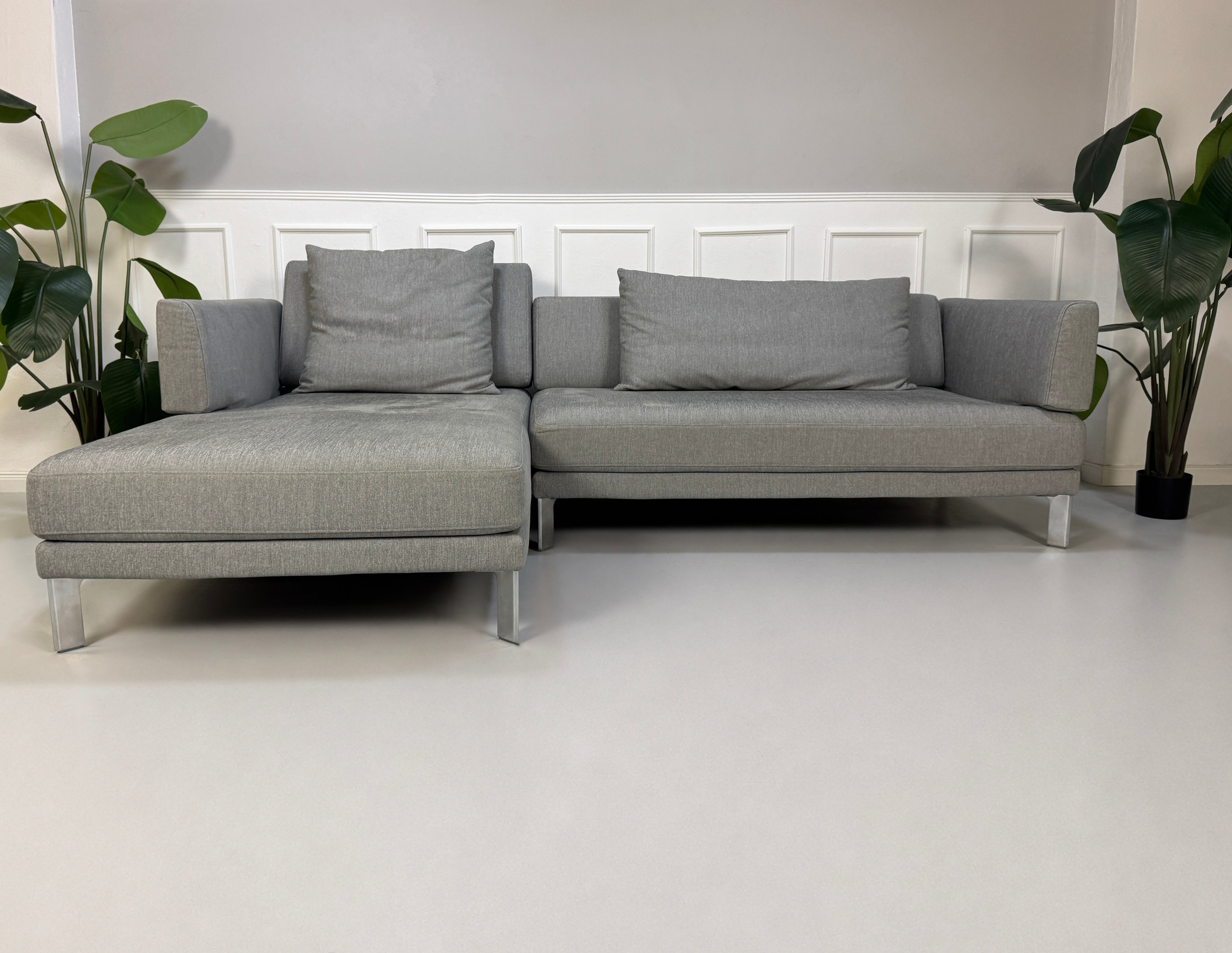 Gebrauchtes graues Rolf Benz Sento Designer Stoff Sofa vor einer Wand, stilvoll und modern eingerichtet.