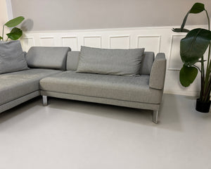 Gebrauchtes graues Rolf Benz Sento Designer Stoff Sofa vor einer Wand, stilvoll und modern eingerichtet.