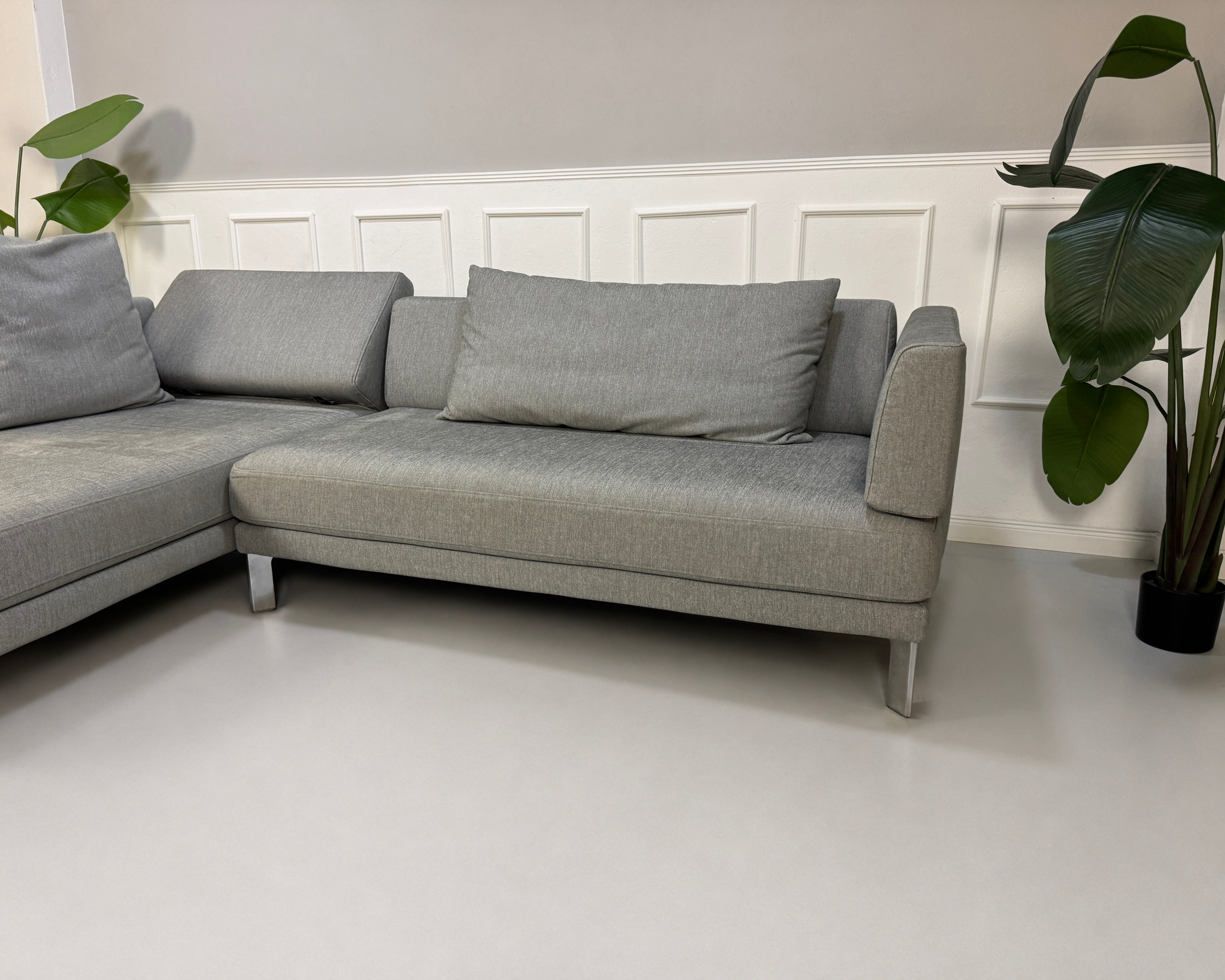 Gebrauchtes graues Rolf Benz Sento Designer Stoff Sofa vor einer Wand, stilvoll und modern eingerichtet.