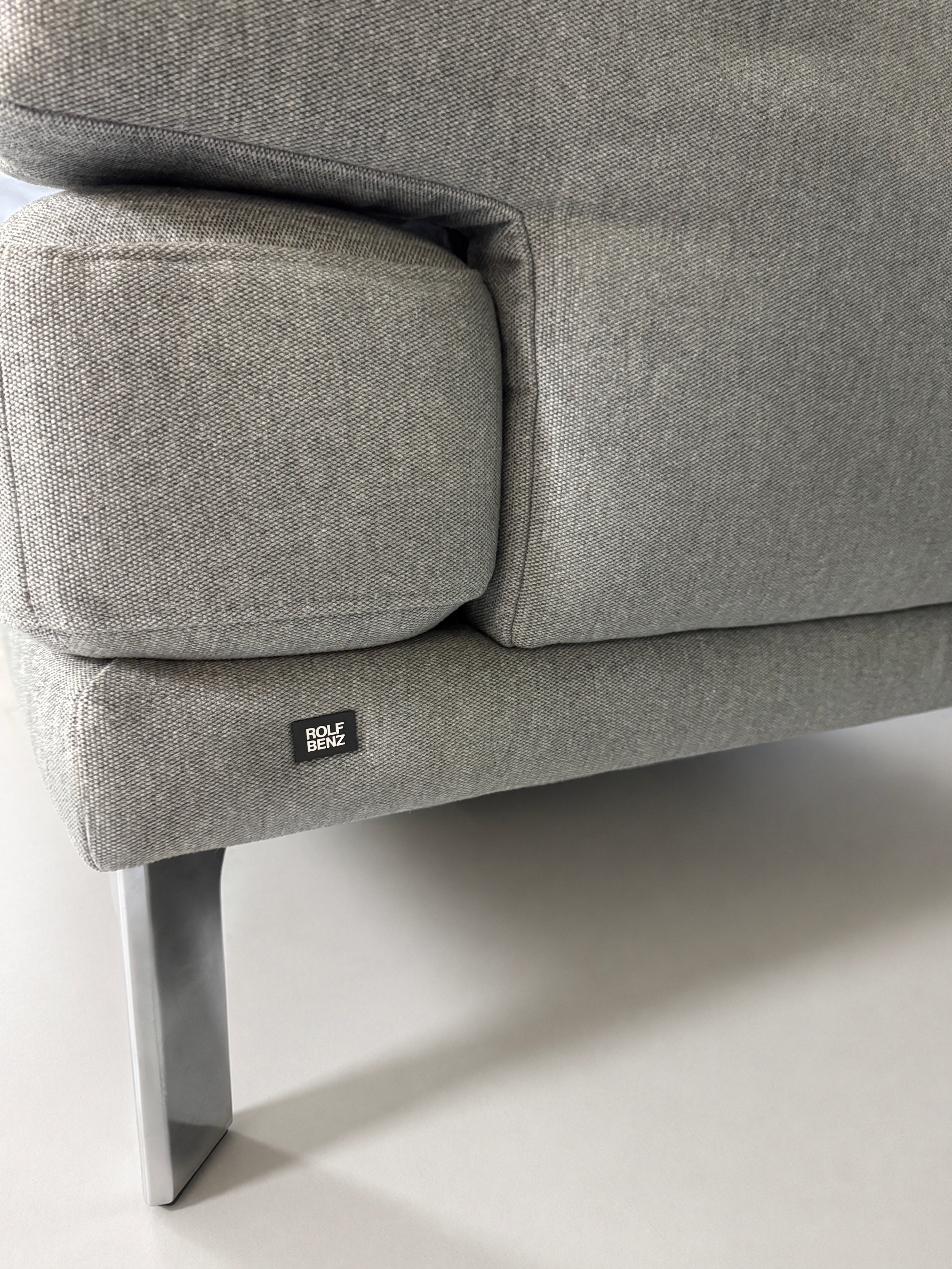 Gebrauchtes graues Rolf Benz Sento Designer Stoff Sofa vor einer Wand, stilvoll und modern eingerichtet.