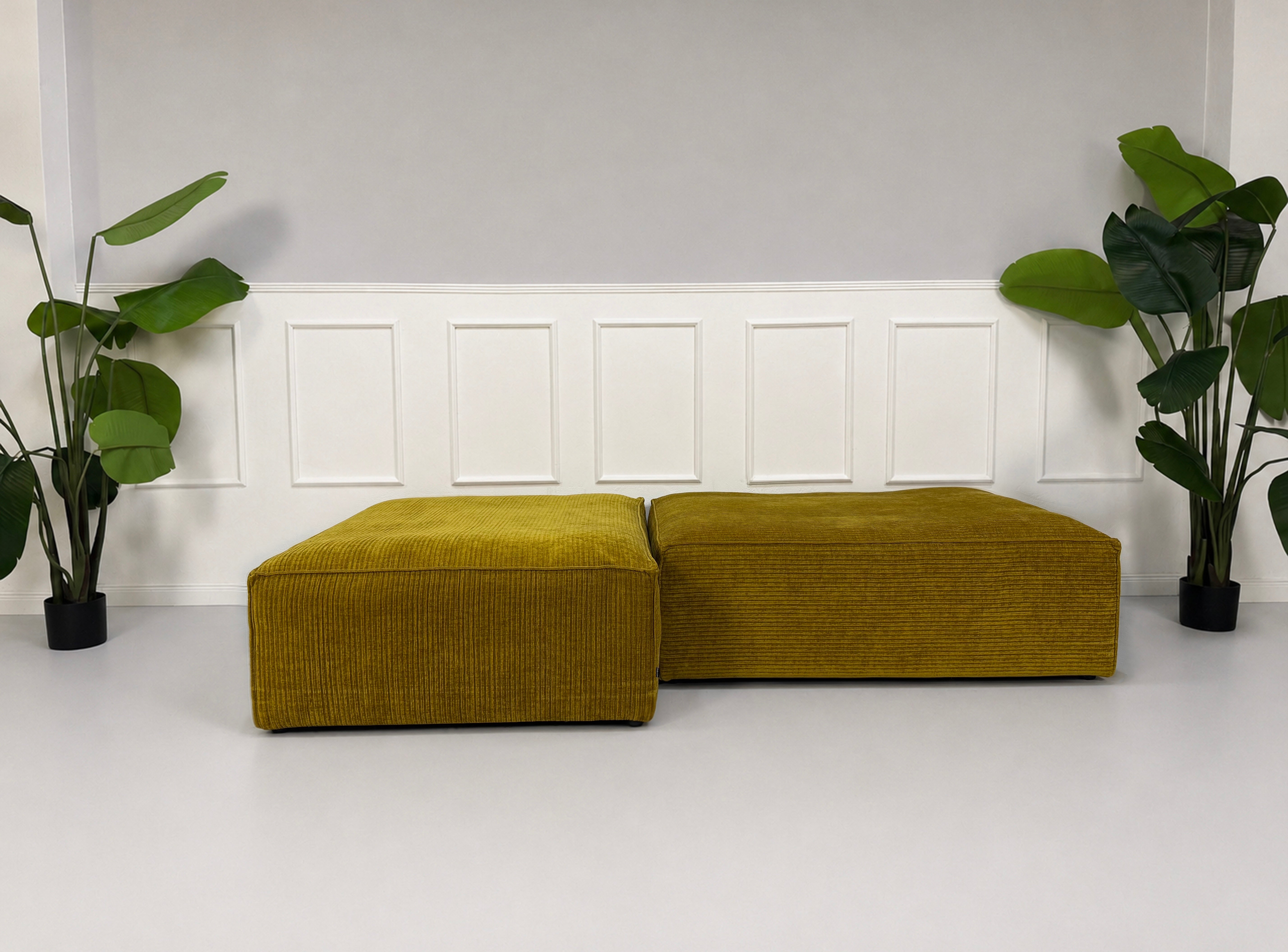 Gebrauchte gelbe Bolia Cosima Designer Cord Hocker vor einer Wand, stilvoll und modern eingerichtet.