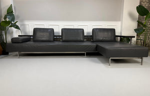 Gebrauchtes graues Rolf Benz Dono Designer Leder Sofa vor einer Wand, stilvoll und modern eingerichtet.