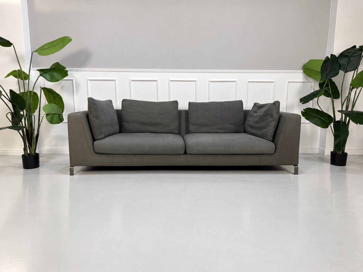 Gebrauchtes graues B&B Italia Ray Designer Stoff Sofa vor einer Wand, stilvoll und modern eingerichtet.
