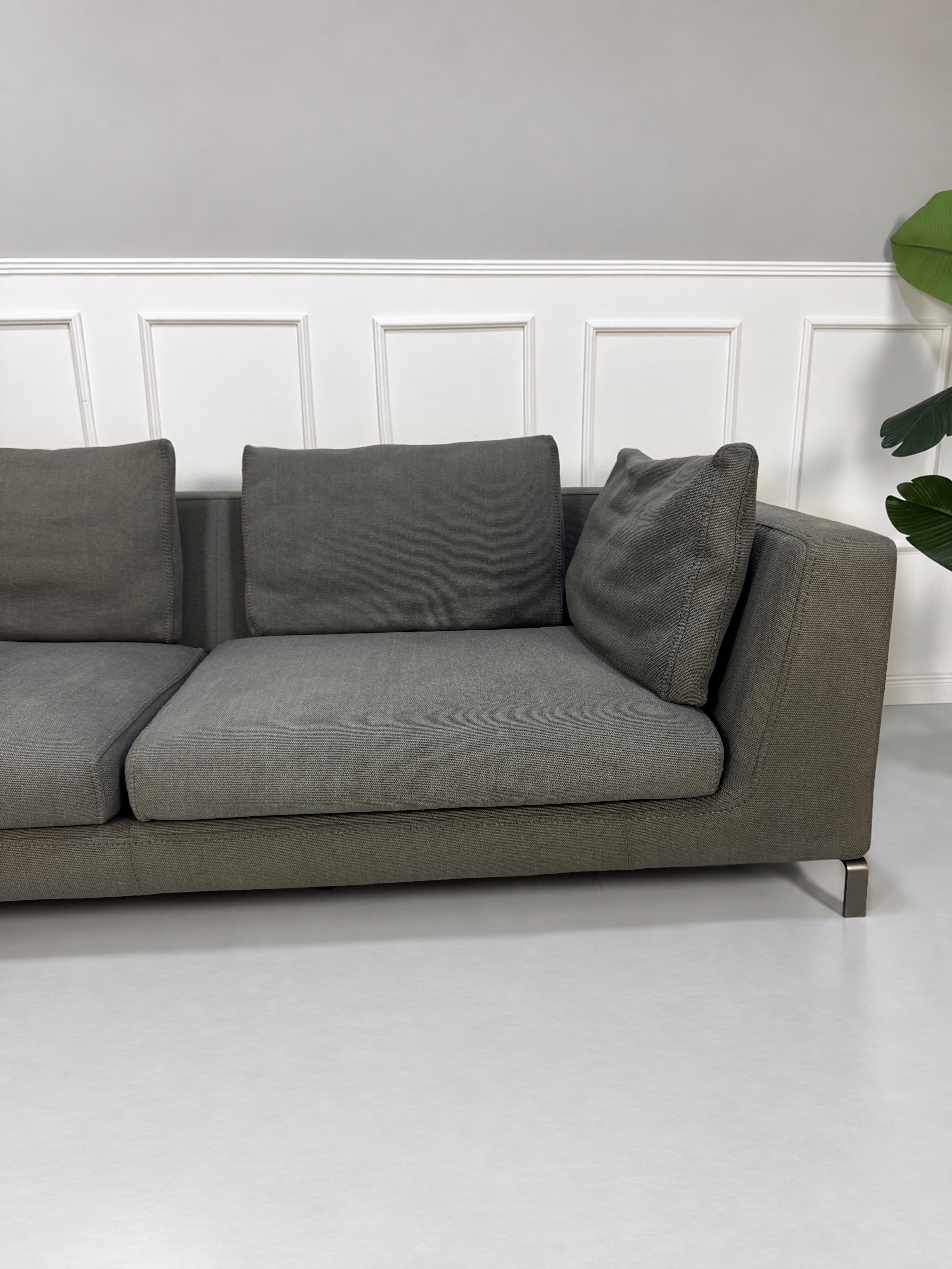 Gebrauchtes graues B&B Italia Ray Designer Stoff Sofa vor einer Wand, stilvoll und modern eingerichtet.