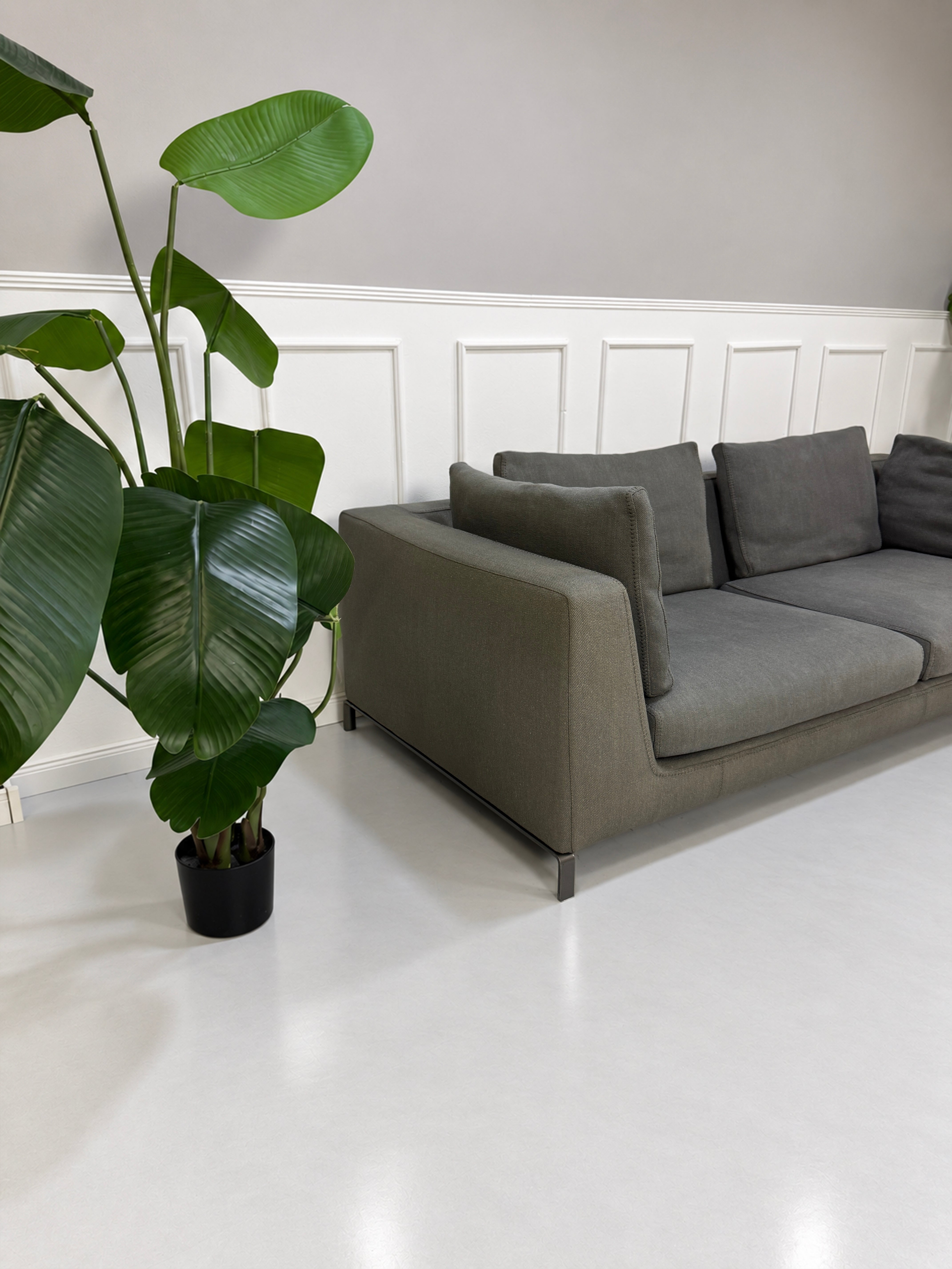 Gebrauchtes graues B&B Italia Ray Designer Stoff Sofa vor einer Wand, stilvoll und modern eingerichtet.