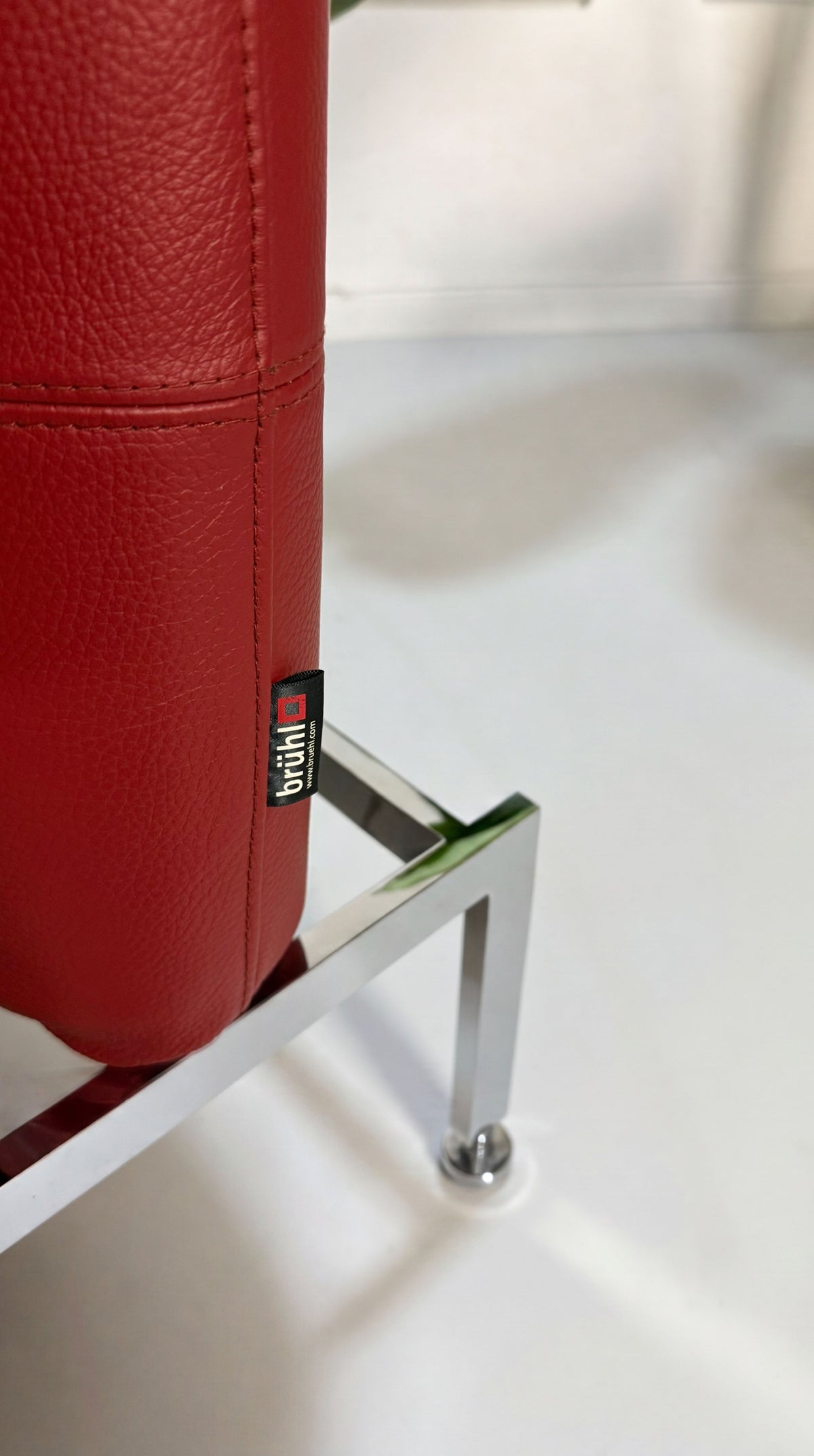 Gebrauchtes rotes Brühl Roro Medium Designer Leder Sofa vor einer Wand, stilvoll und modern eingerichtet.