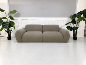 Gebrauchtes grau-beiges Bolia Núvol Designer Stoff Sofa vor einer Wand, stilvoll und modern eingerichtet.