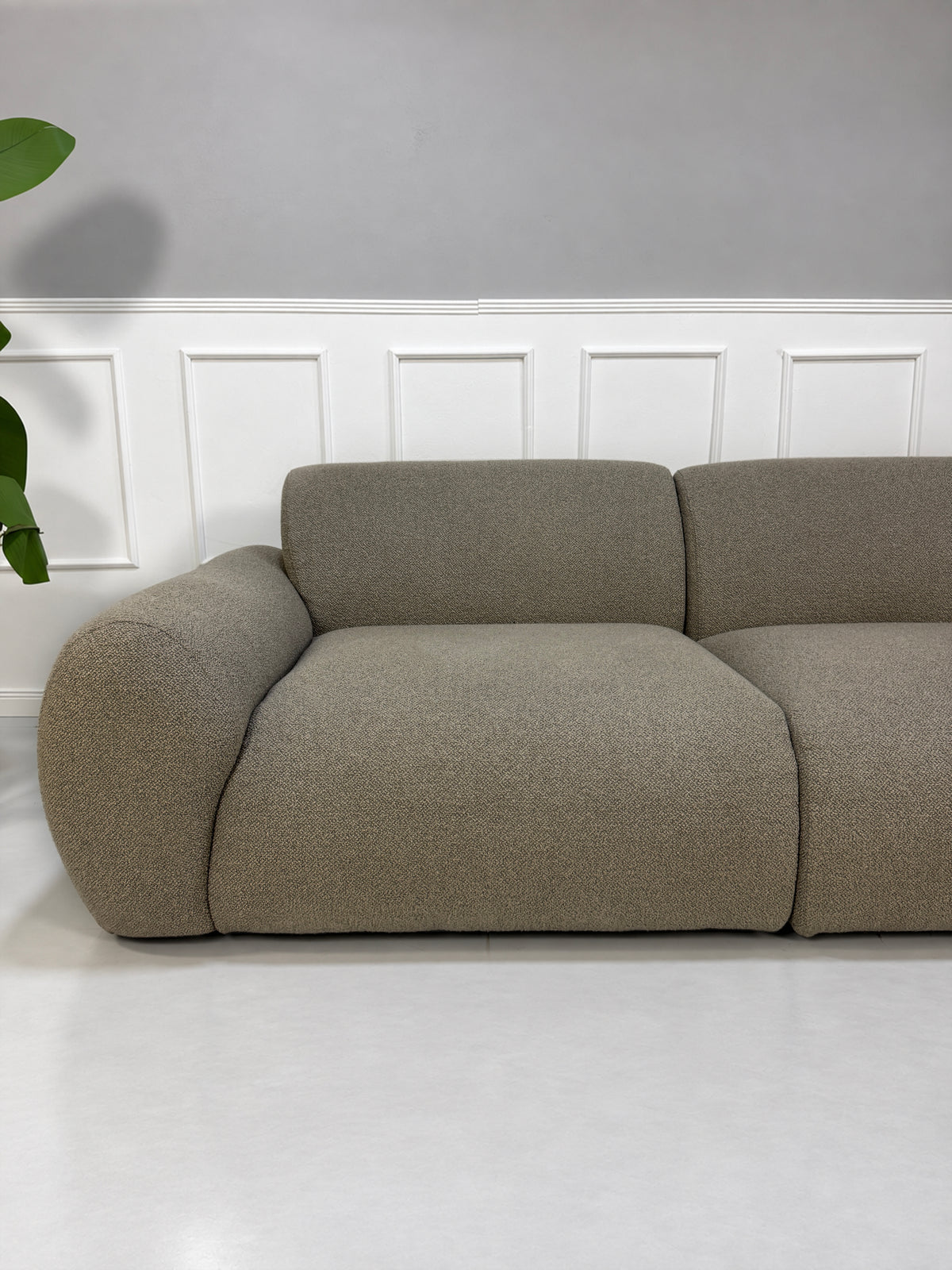 Gebrauchtes grau-beiges Bolia Núvol Designer Stoff Sofa vor einer Wand, stilvoll und modern eingerichtet.