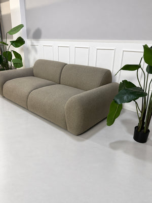 Gebrauchtes grau-beiges Bolia Núvol Designer Stoff Sofa vor einer Wand, stilvoll und modern eingerichtet.